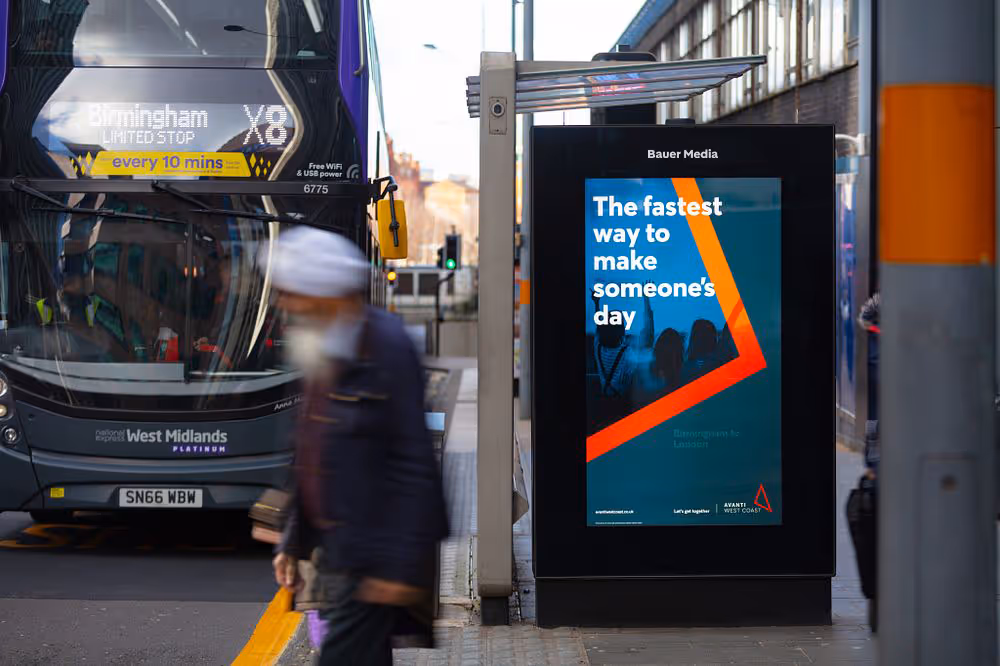 Avanti West Coast's blue orange and grey travel advertisement with a bus stationed at a bus stop