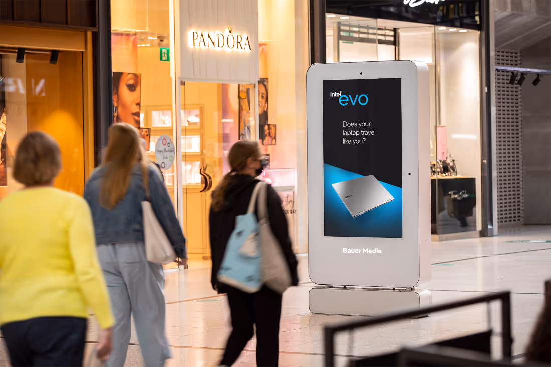 Evo advert on digital screen in shopping mall with people walking past