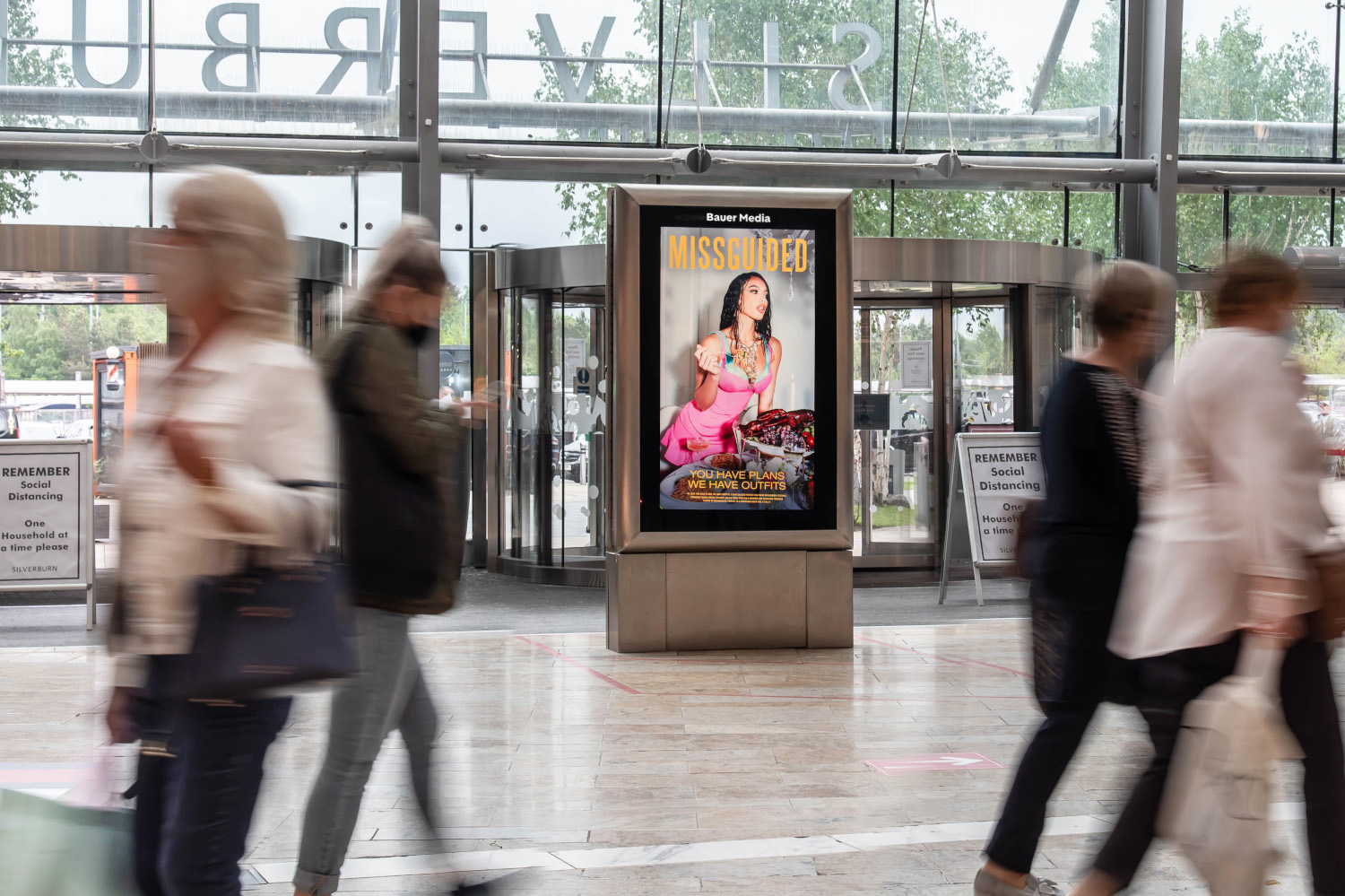 Missguided advert on digital screen in shopping mall with people walking past