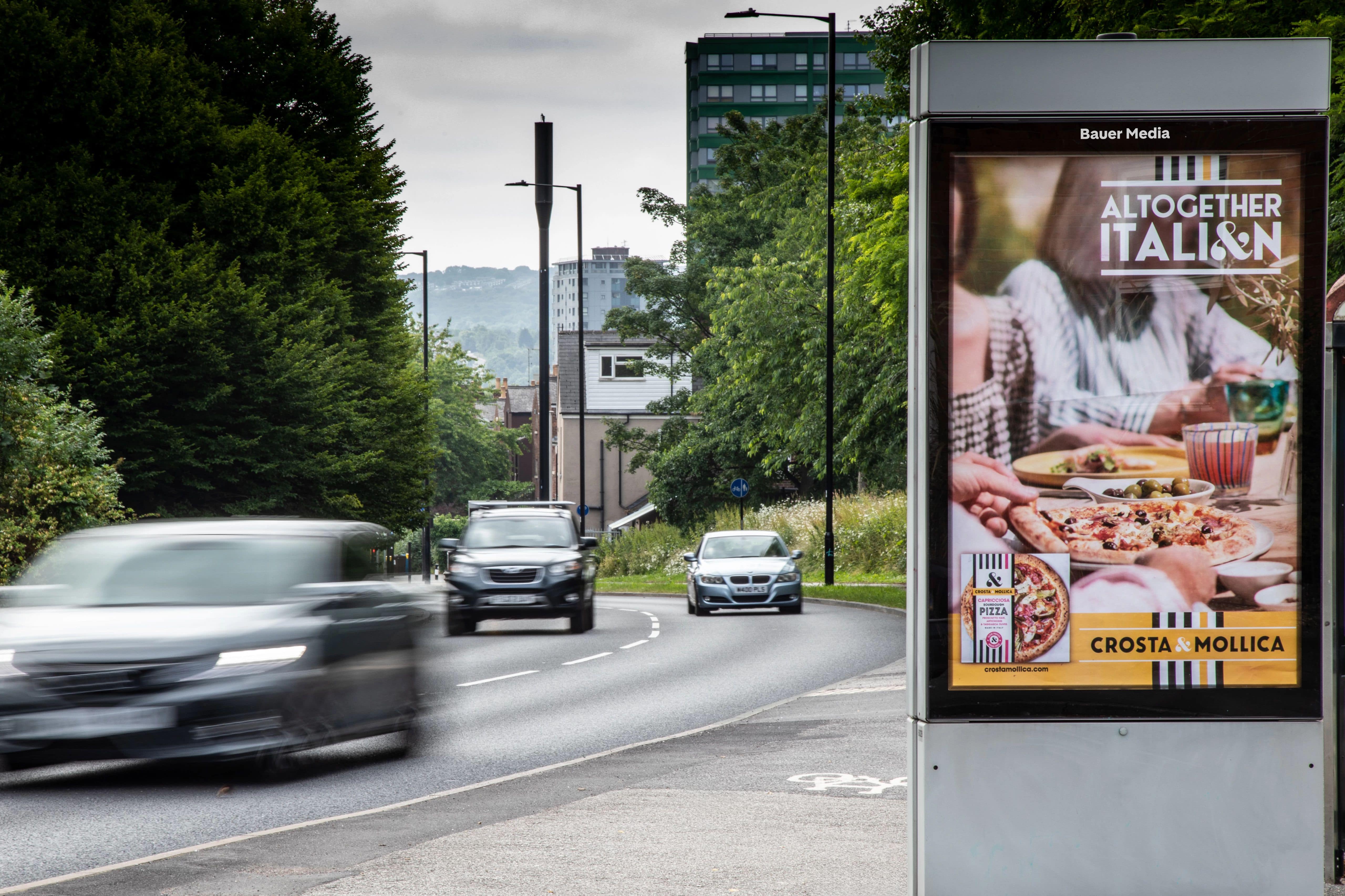 A classic bus shelter advertisement on a busy road