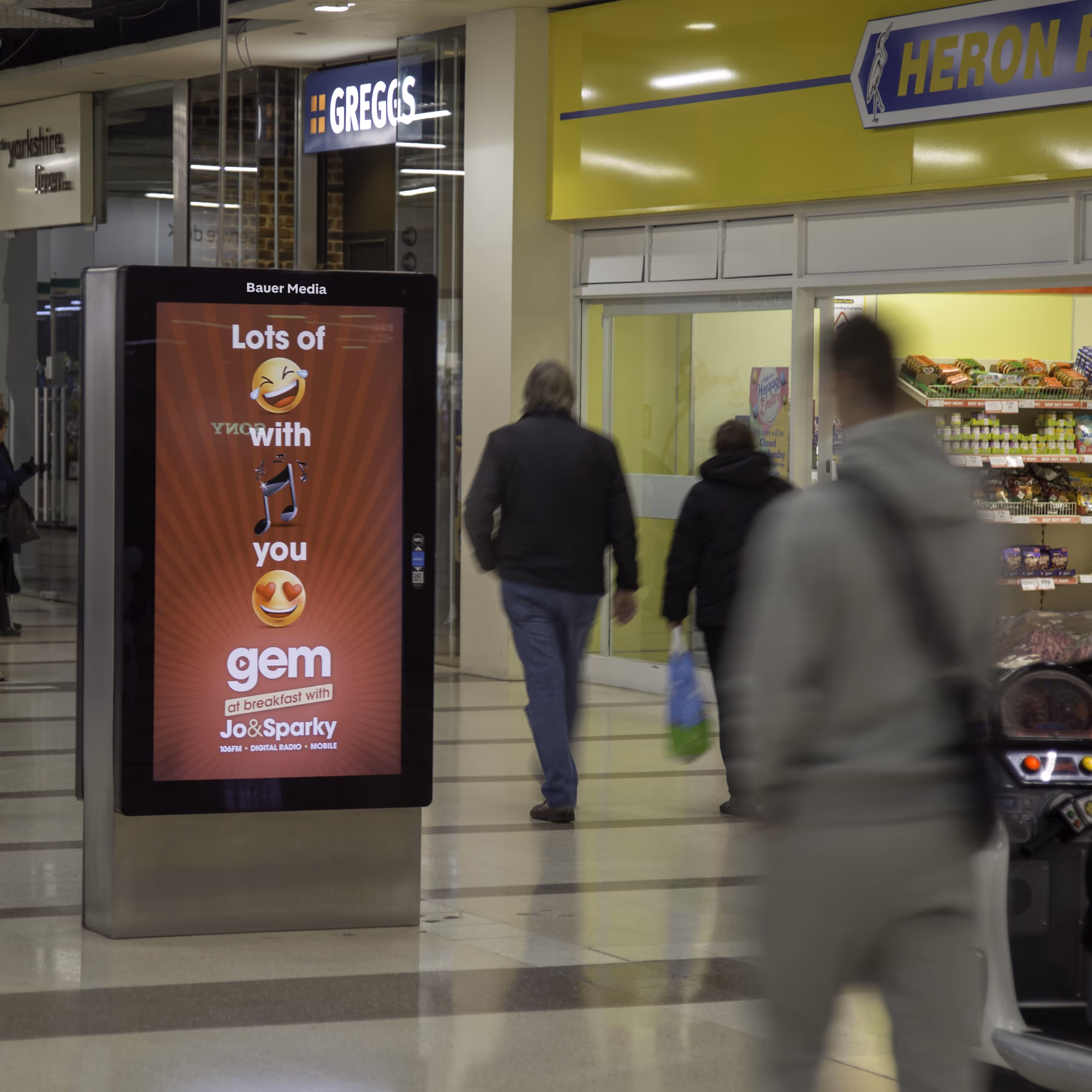 Gem Radio advertising outside of Heron Foods on a digital screen inside a shopping mall