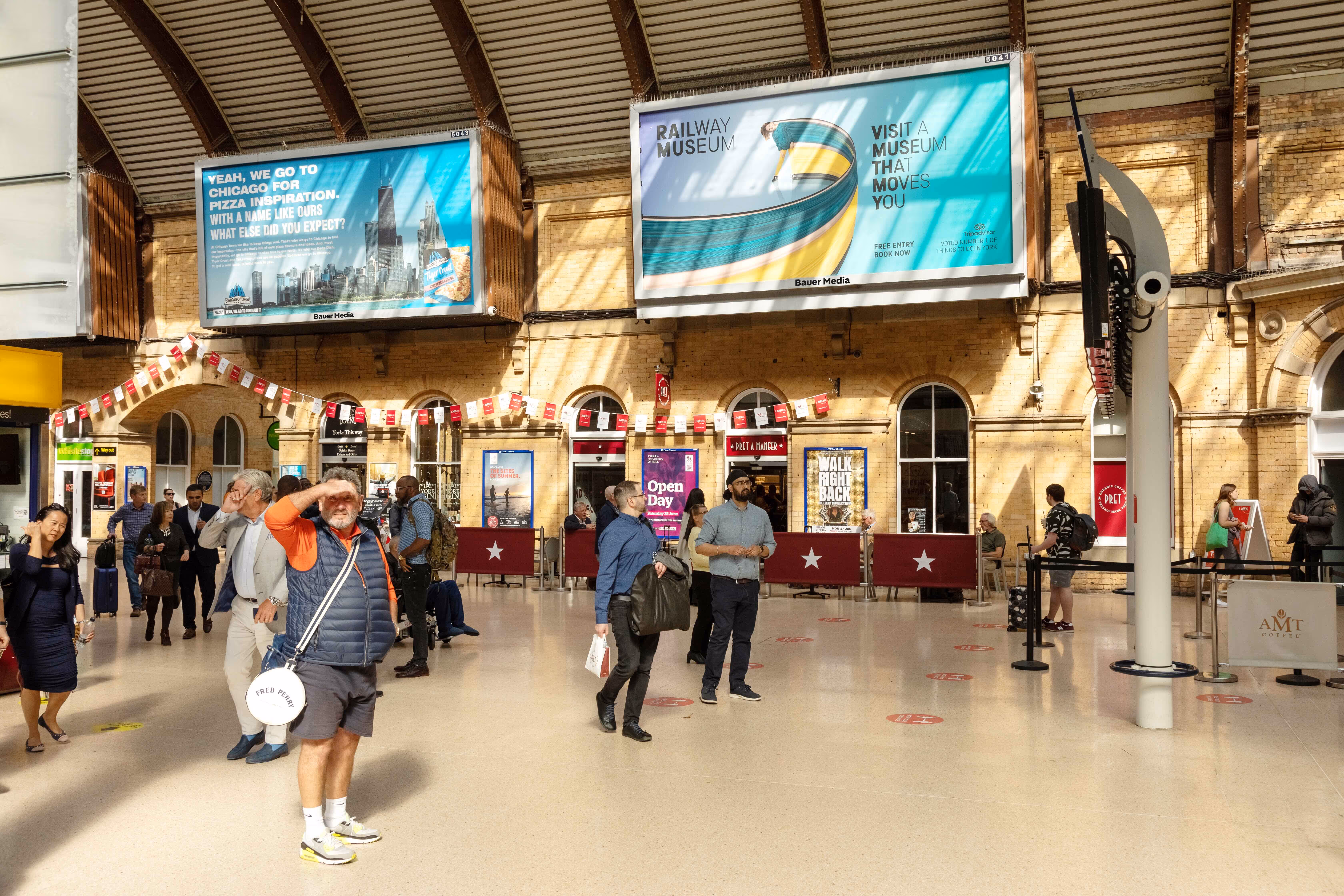 Rail station concourse with two billboards showing ads for Railway Museum & Chicago Town pizza