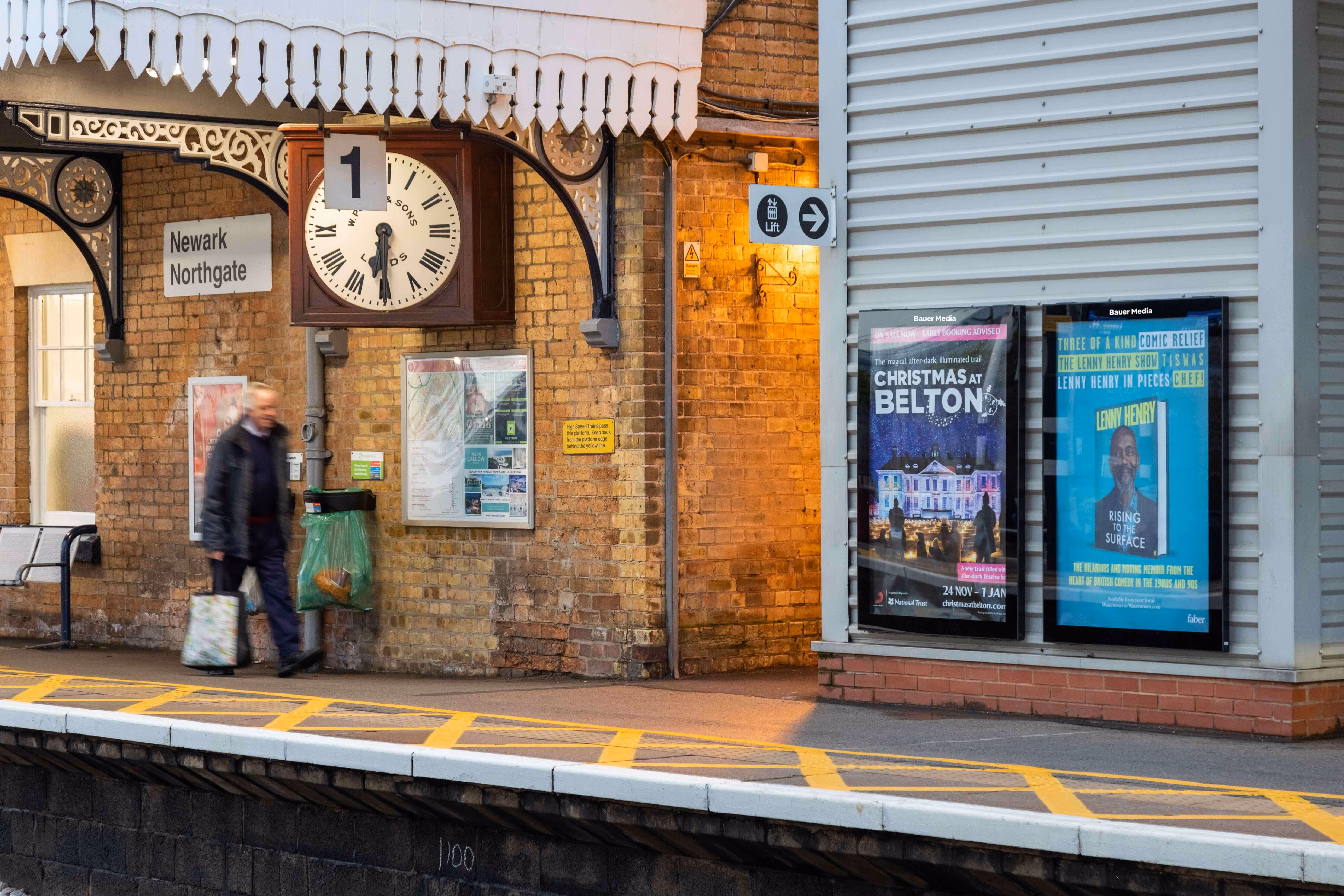 Rail platform with two billboards showing ads for National trust & Lenny Henry biography