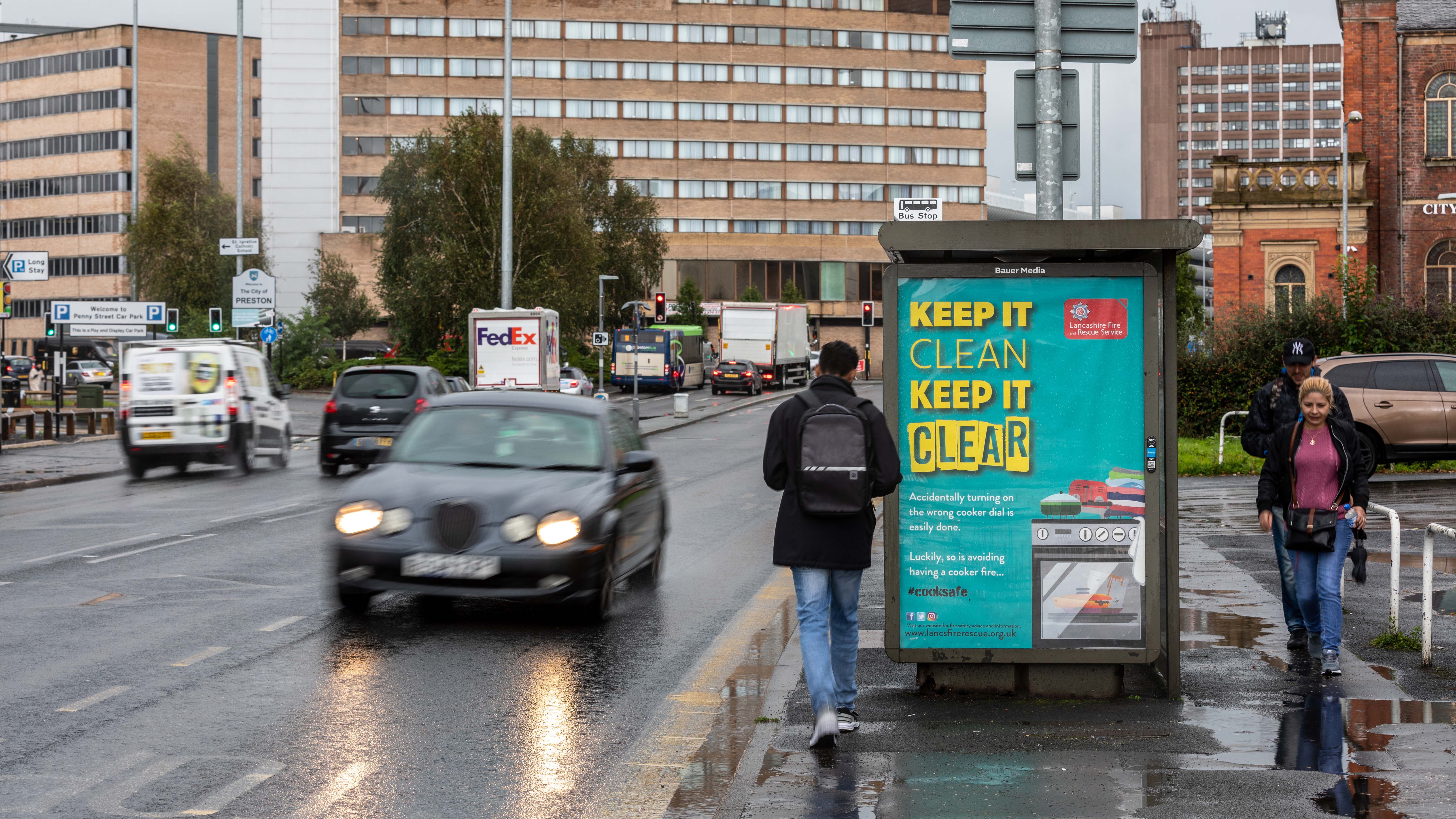 A 'safe cooking' advert on a roadside bus stop poster in the rain
