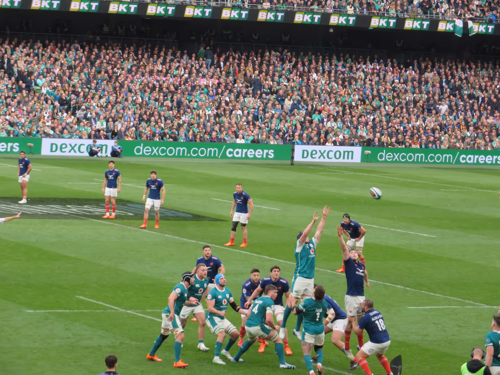 A pitch-side LED advertising board displaying Dexcom, with players competing for a lineout in the foreground during Ireland & France, in the Aviva Stadium