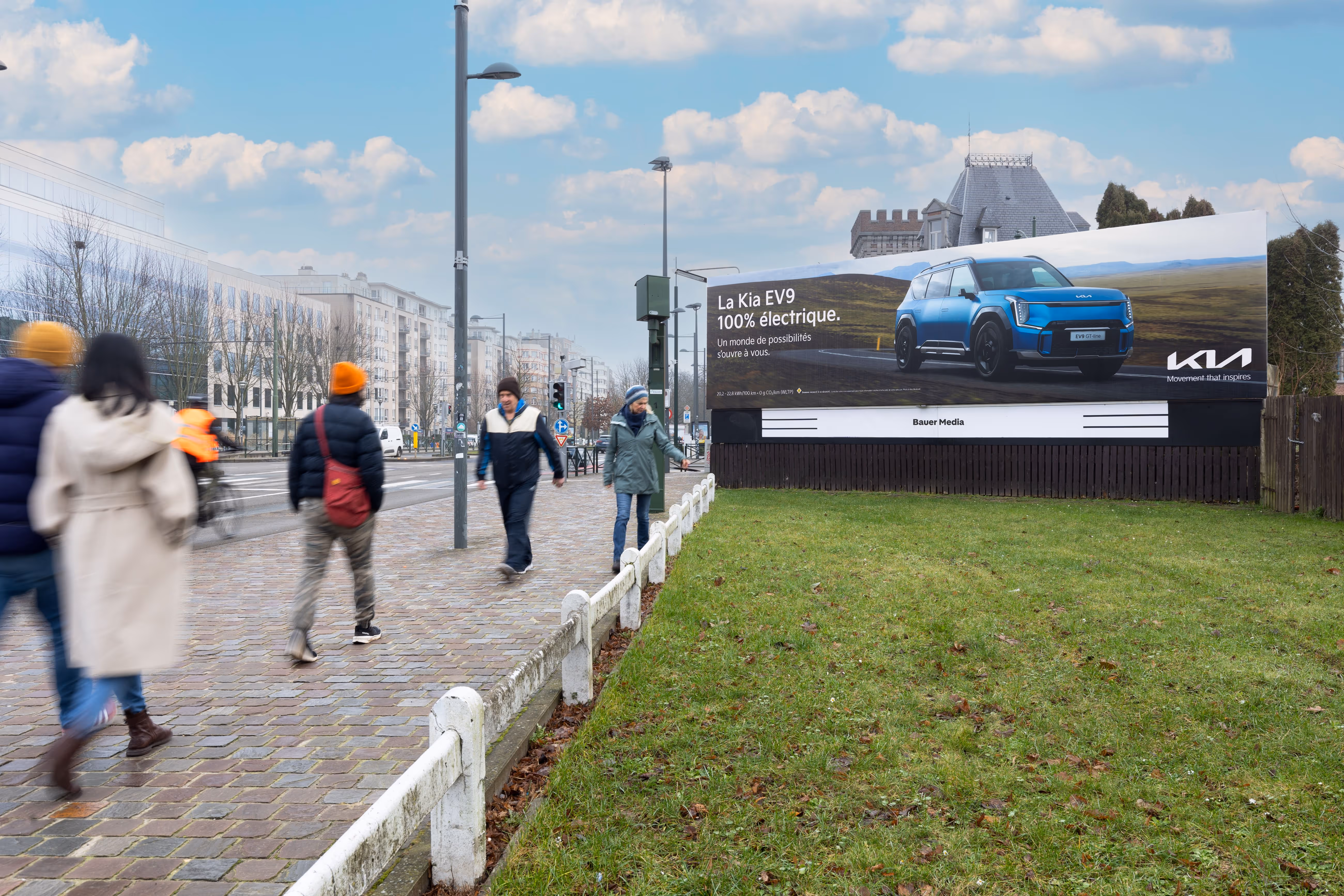 A digital advertisement on a busy London road with people and traffic passing by