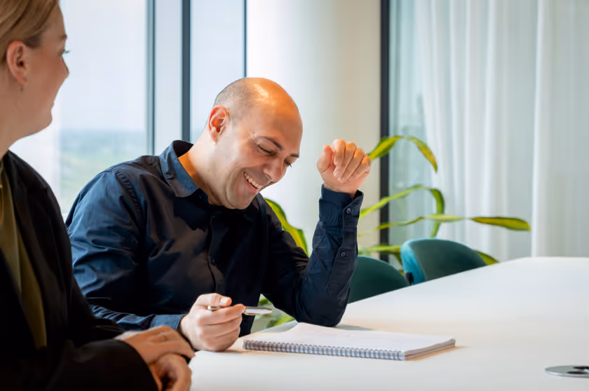 Medewerker kijkt lachend naar vel papier.
