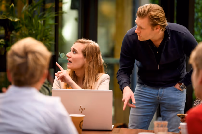 Vrouw wijst naar scherm en de man die naast haar staat kijkt mee. 