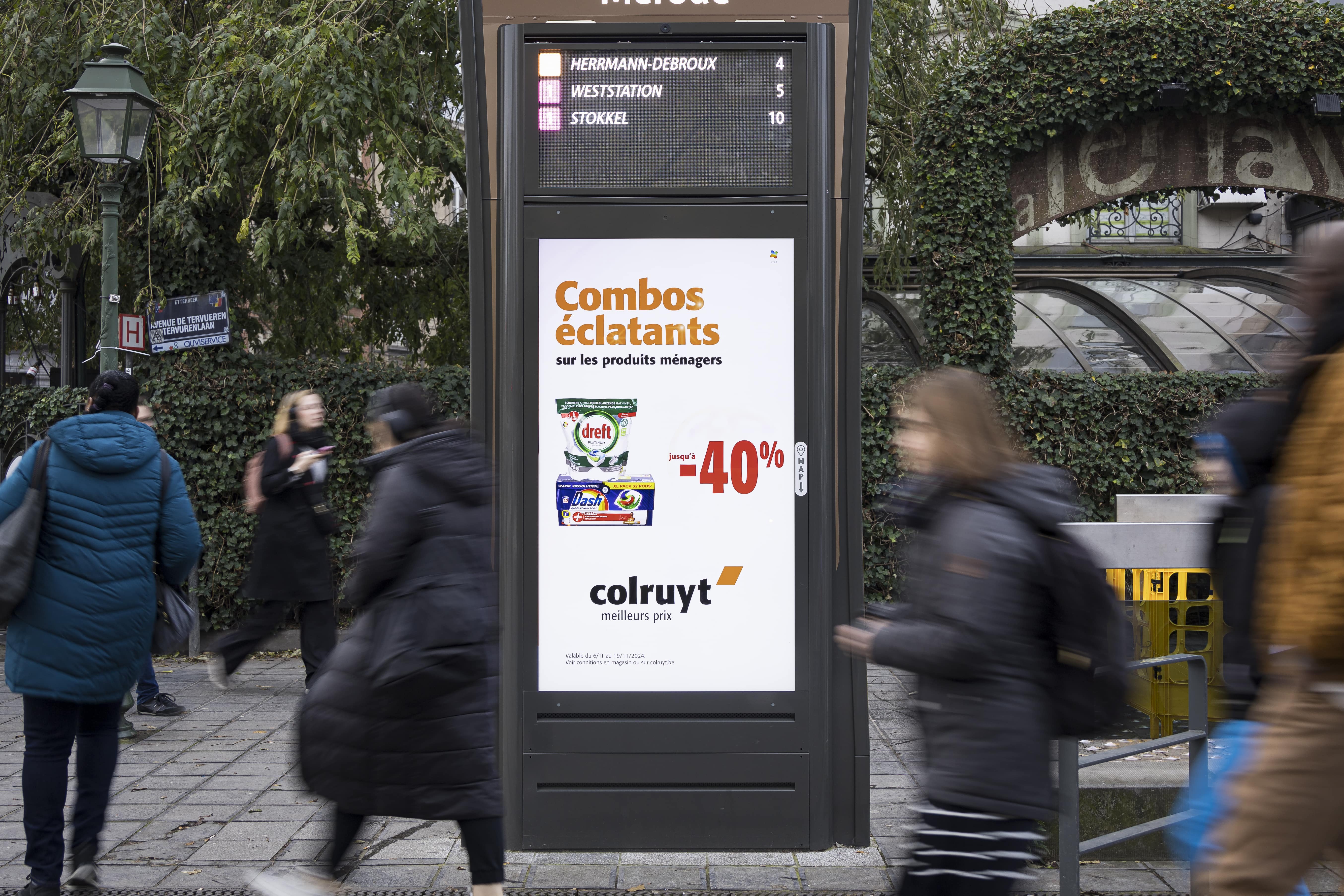 Digital advertisement on the station platform with commuters waiting for their train
