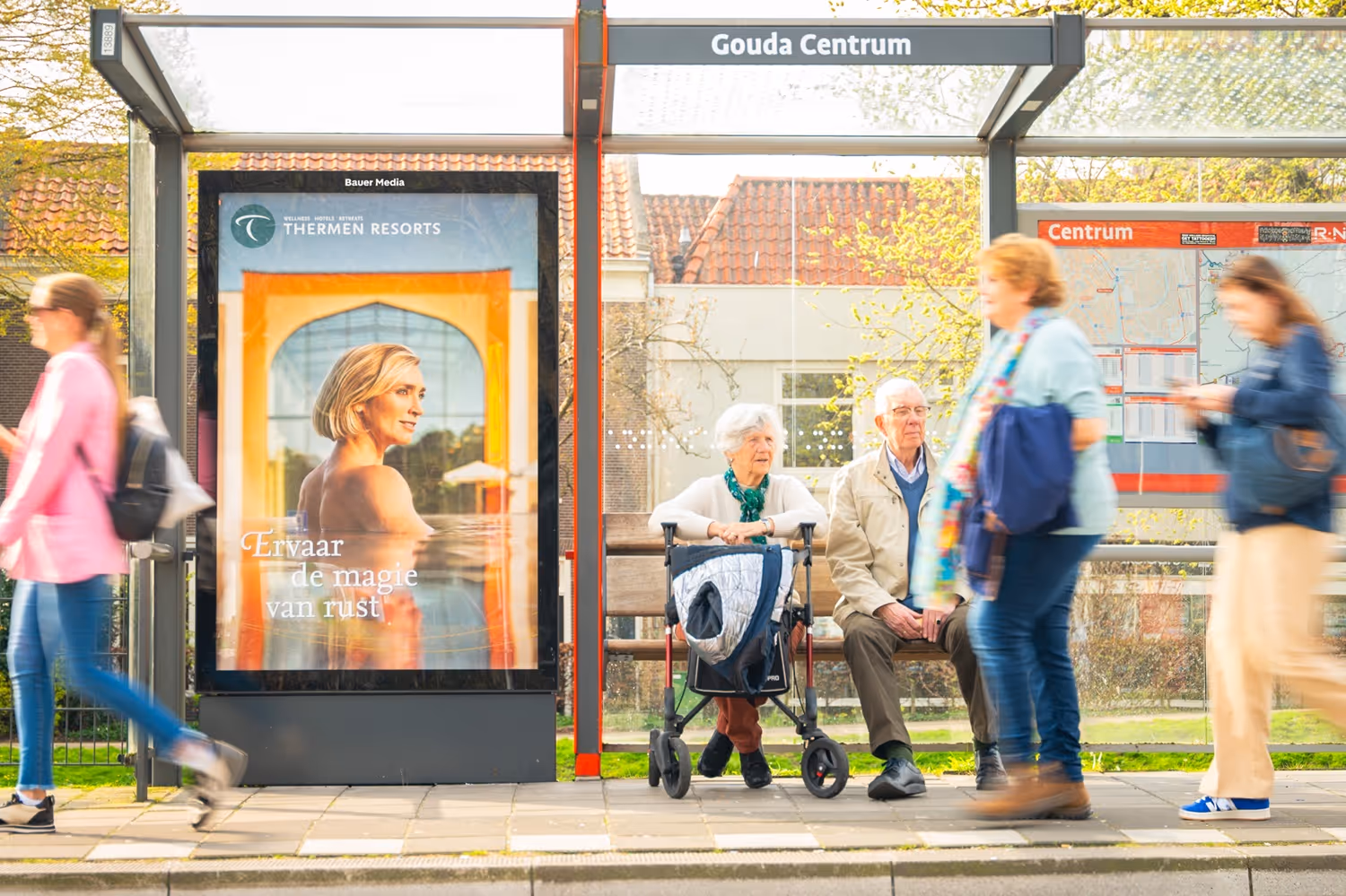 Bushalte in Gouda Centrum met voorbijgangers en wachtende mensen.