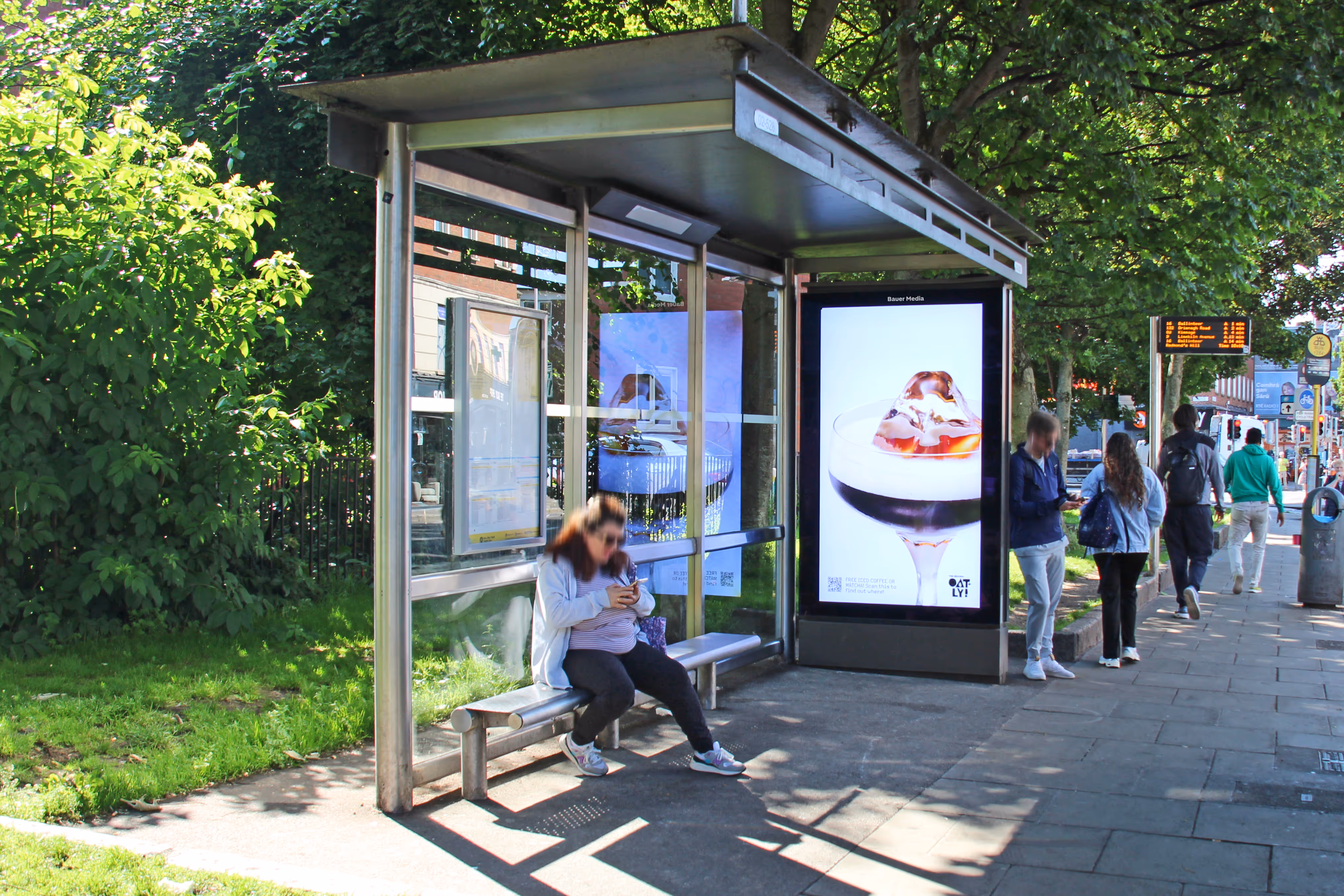 An Adshel Live bus shelter on a Dublin City street displaying an advertisement for Oatly