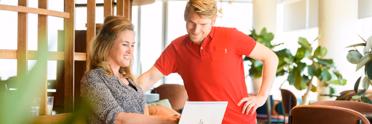 Man en vrouw met elkaar in gesprek en kijkend naar laptop.
