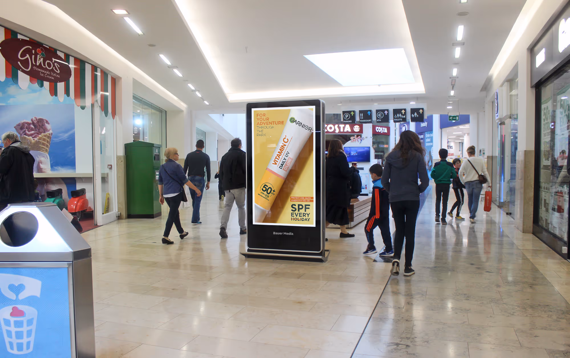 Digital advertisement inside a shopping centre with shoppers walking past