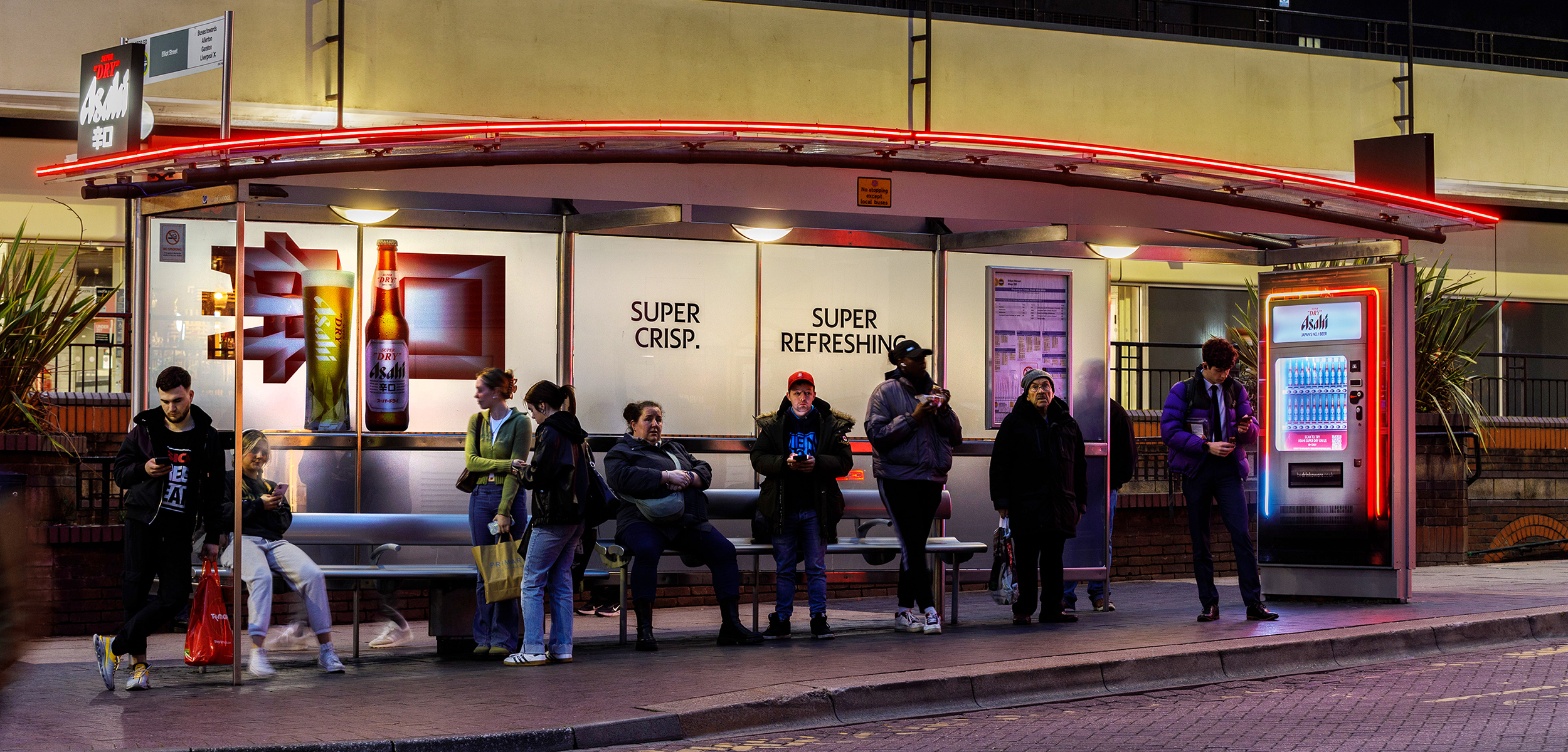 People at a bus shelter, which is creatively wrapped by advertiser Asahi
