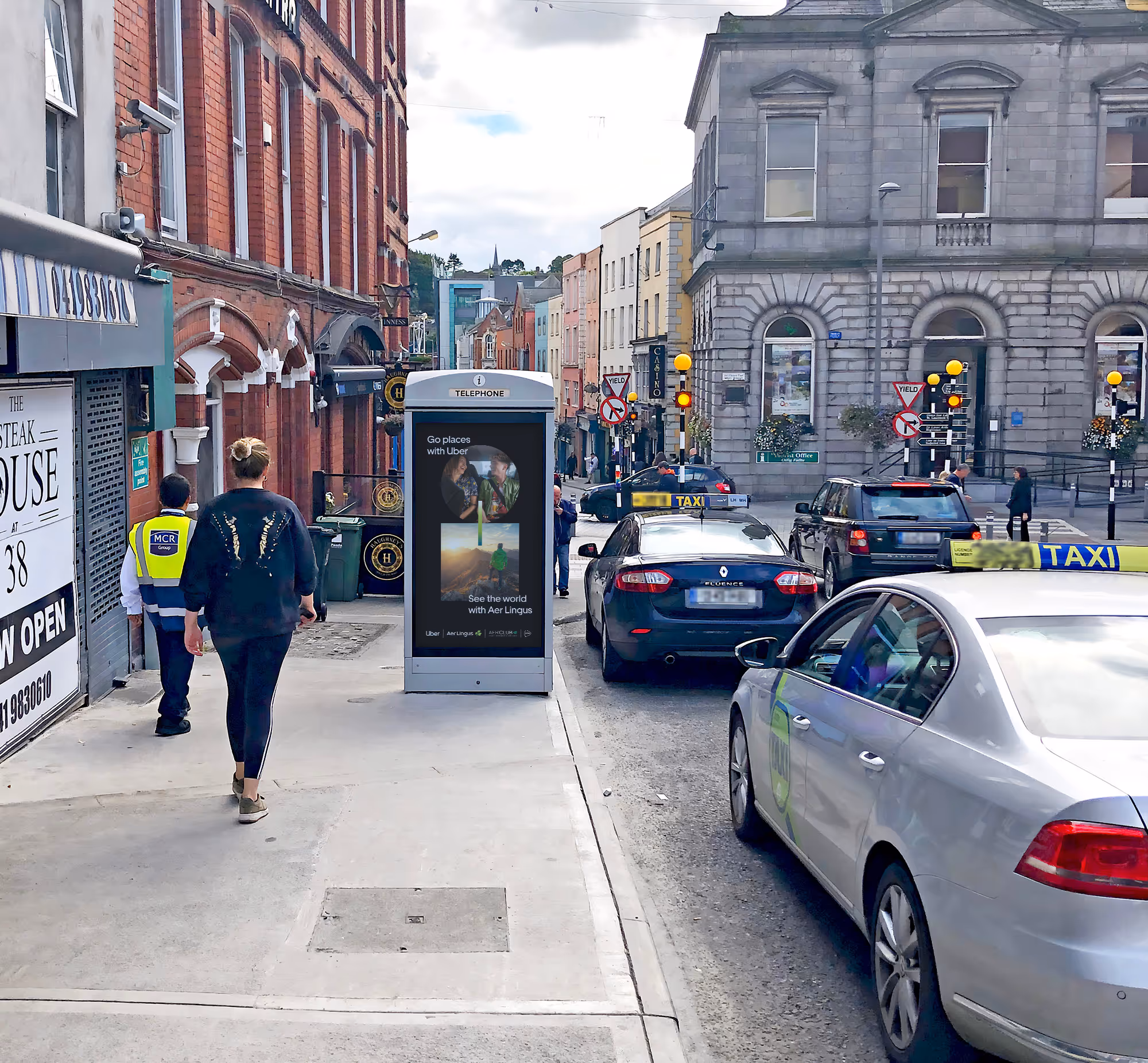 An Adshel Live kiosk located in a busy town centre with cars and pedestrians