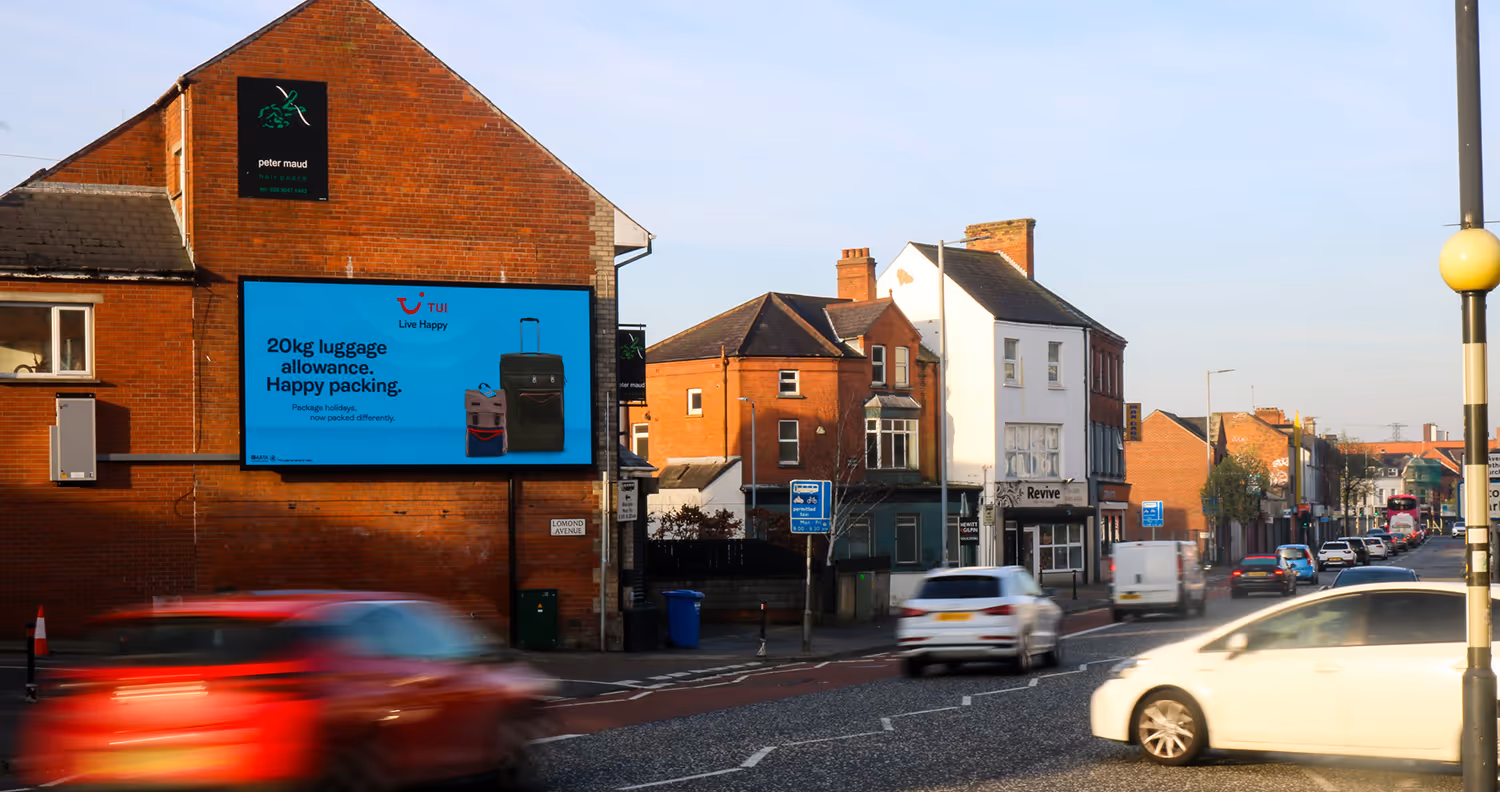 a digital billboard located on a busy street surrounded by shops and residential buildings