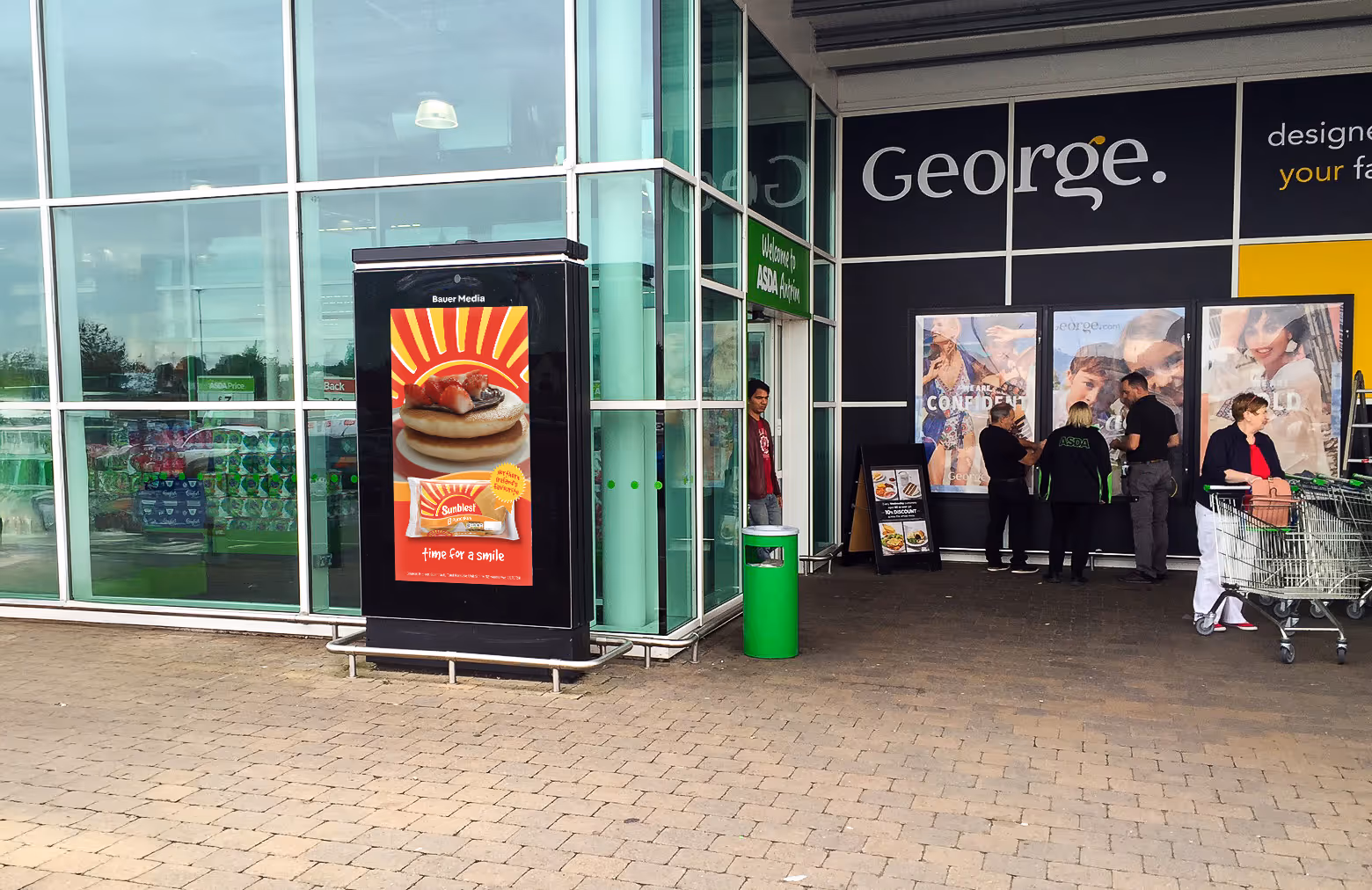 Digital advertisement outside of a Asda entrance with shoppers walking by