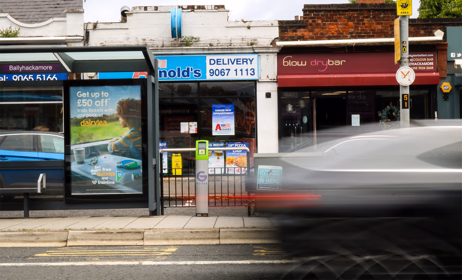 a bus shelter advertisement on a busy shop street with traffic passing by