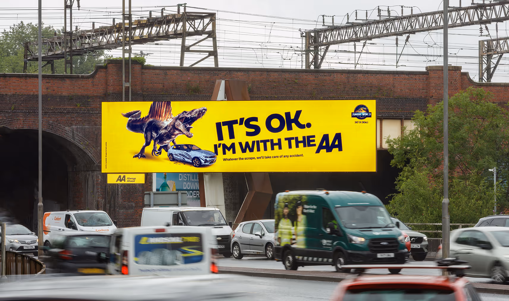 An AA advert, it's bright yellow, as traffic drives past on a busy road.