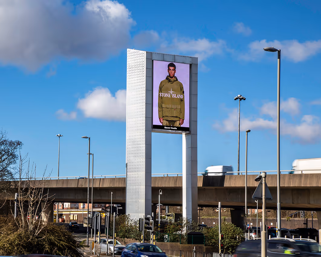 A large architectural structure with a dooh billboard next to a motorway.