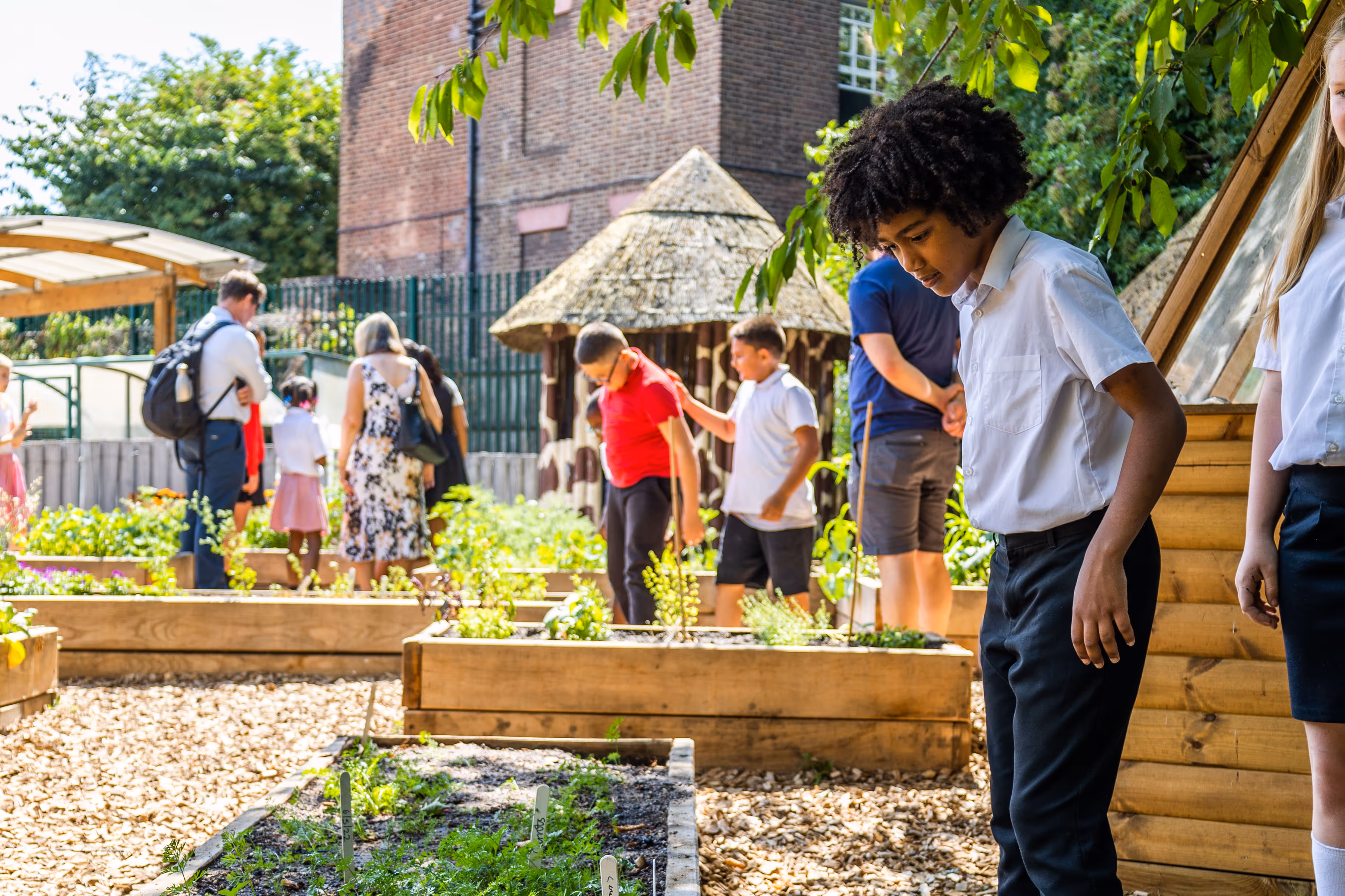 School children looking in the plants in the flower beds of the edible playground