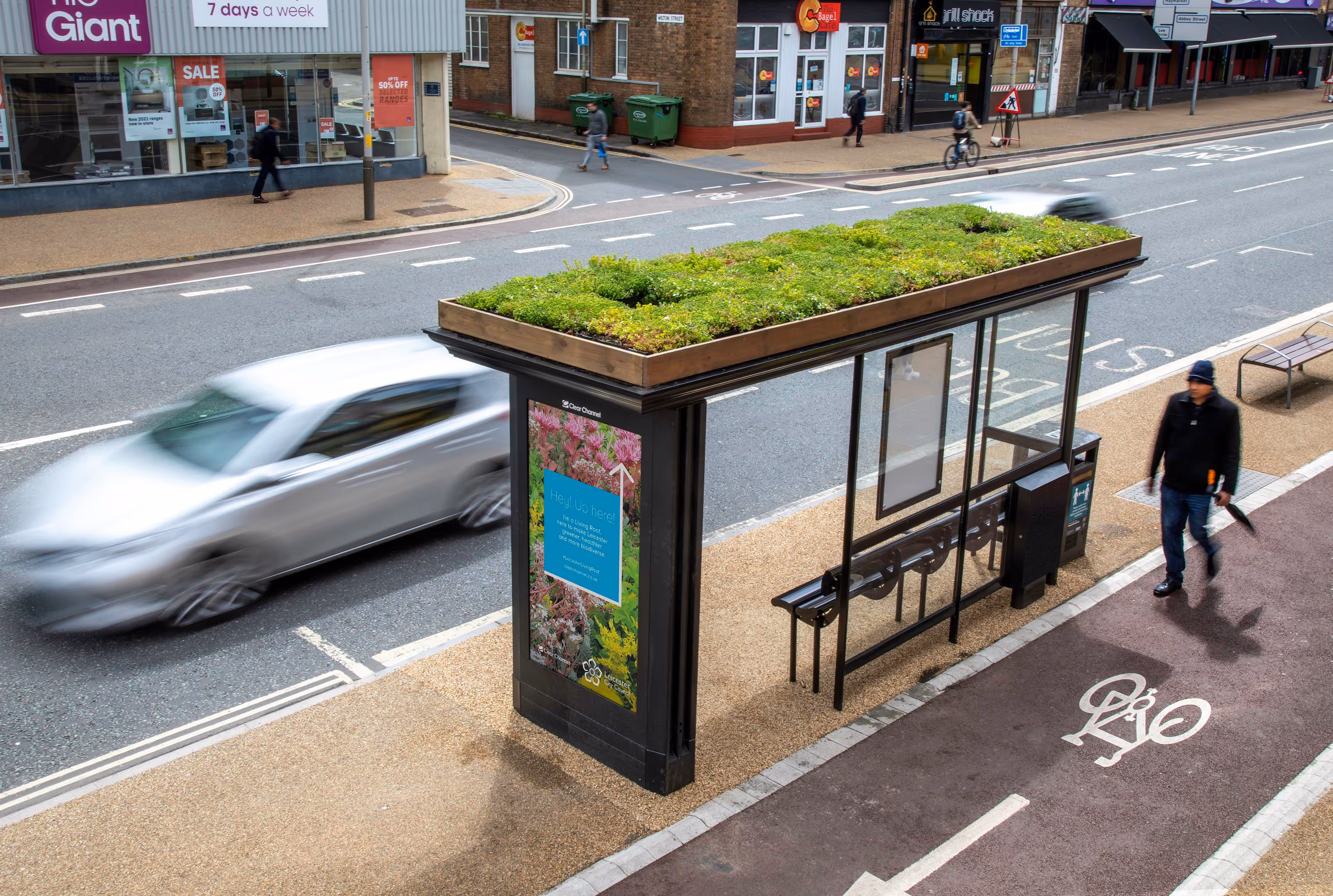 Adshel screen with text saying 'Hey up here!' on a Clear Channel 'Living Roof' bus shelter