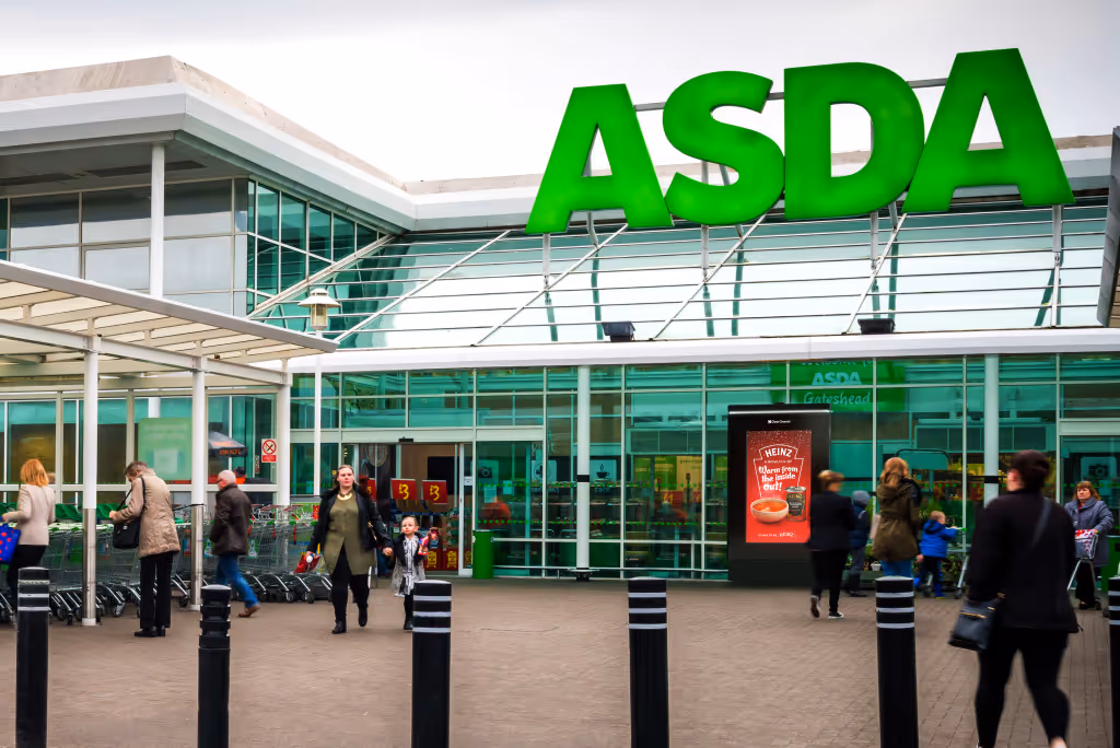 A Heinz advert features on a digital screen outside and ASDA as shoppers exit and enter the store, during the day