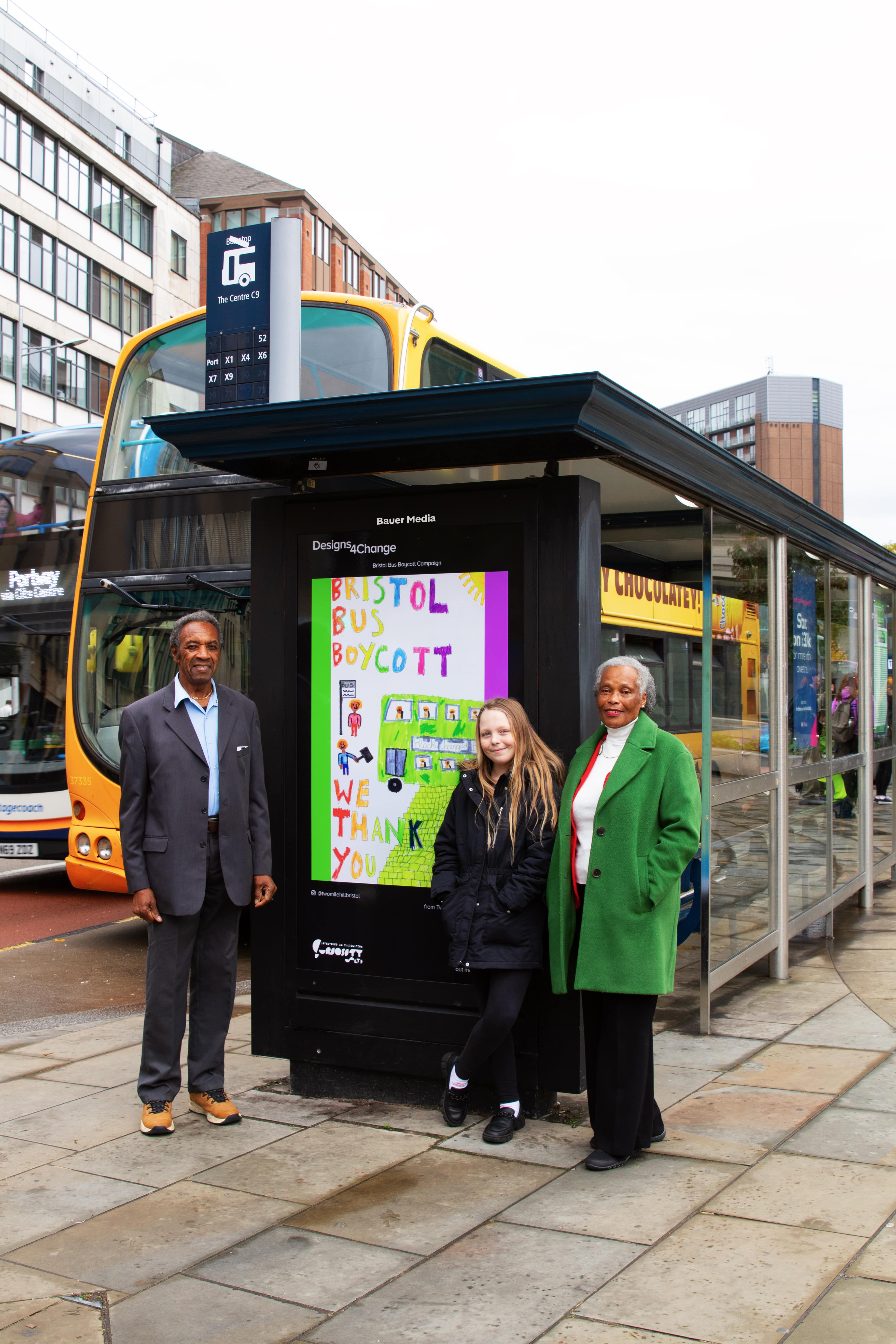 Martha Clarke and Bristol Bus Boycott pioneers at a bus stop displaying her winning image during the day