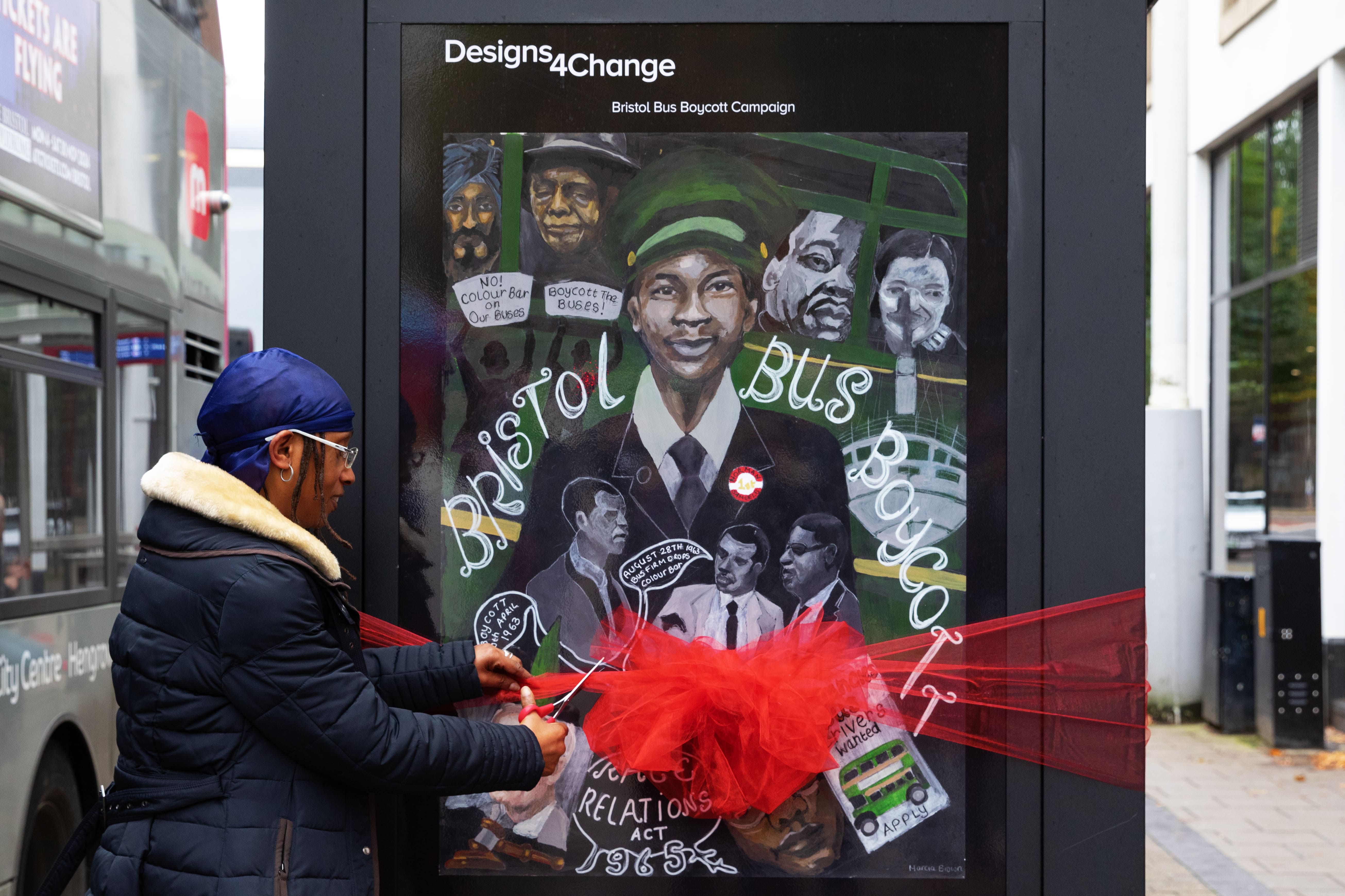 Marcia Brown cutting a ribbon wrapped around their winning image during the day