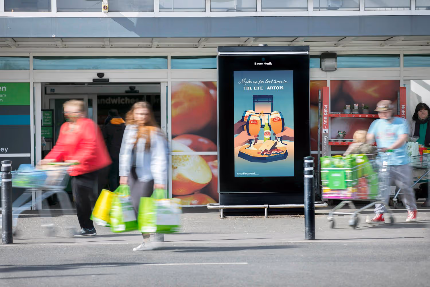 Digital 6-sheet advertising panel outside a busy supermarket