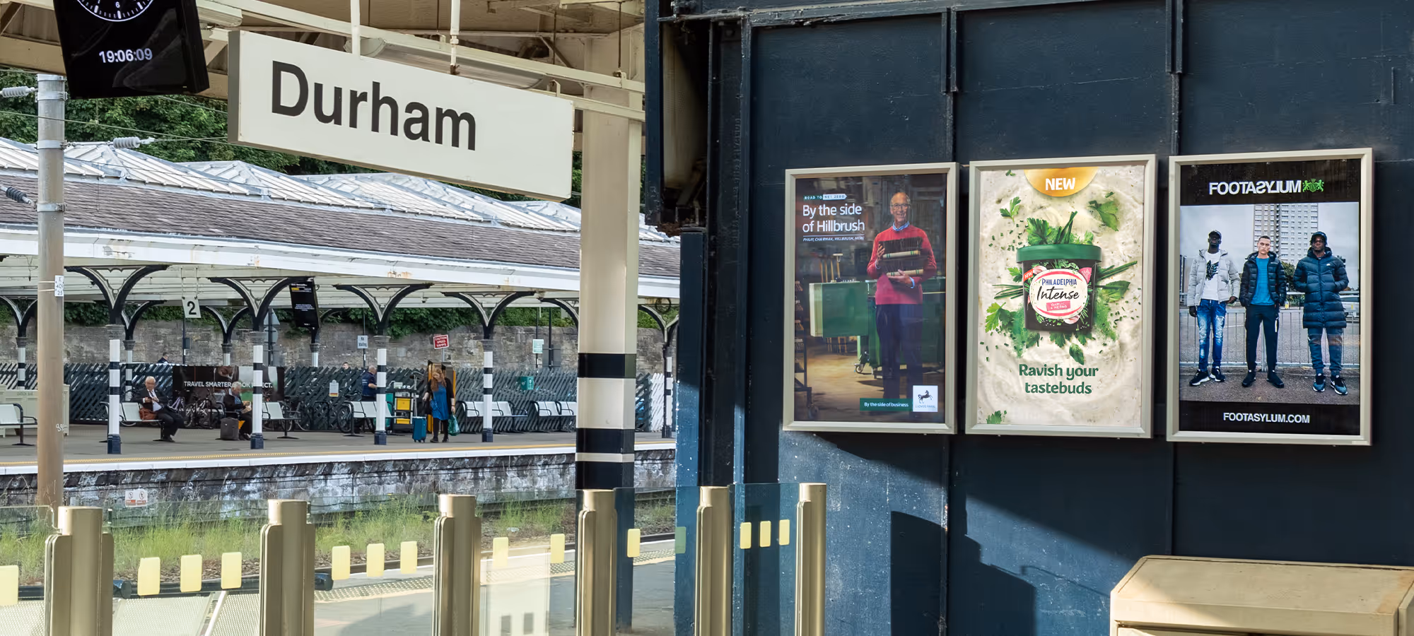 Set of 3 small poster adverts on an outdoor train station concourse