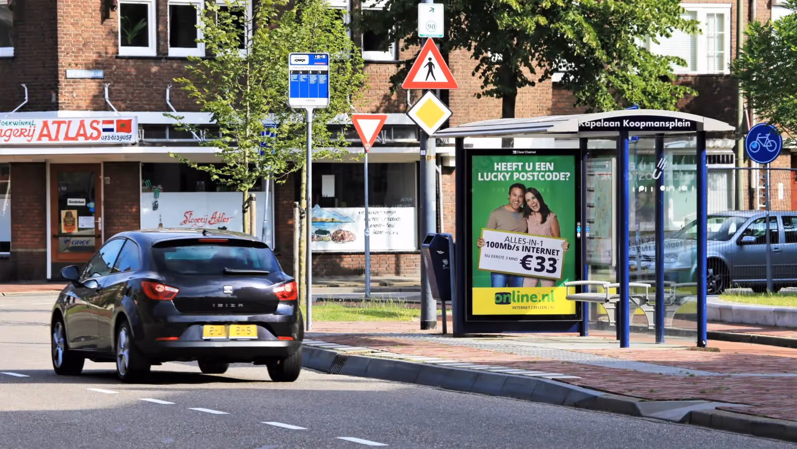 Bushalte met reclame en voorbijgaande auto