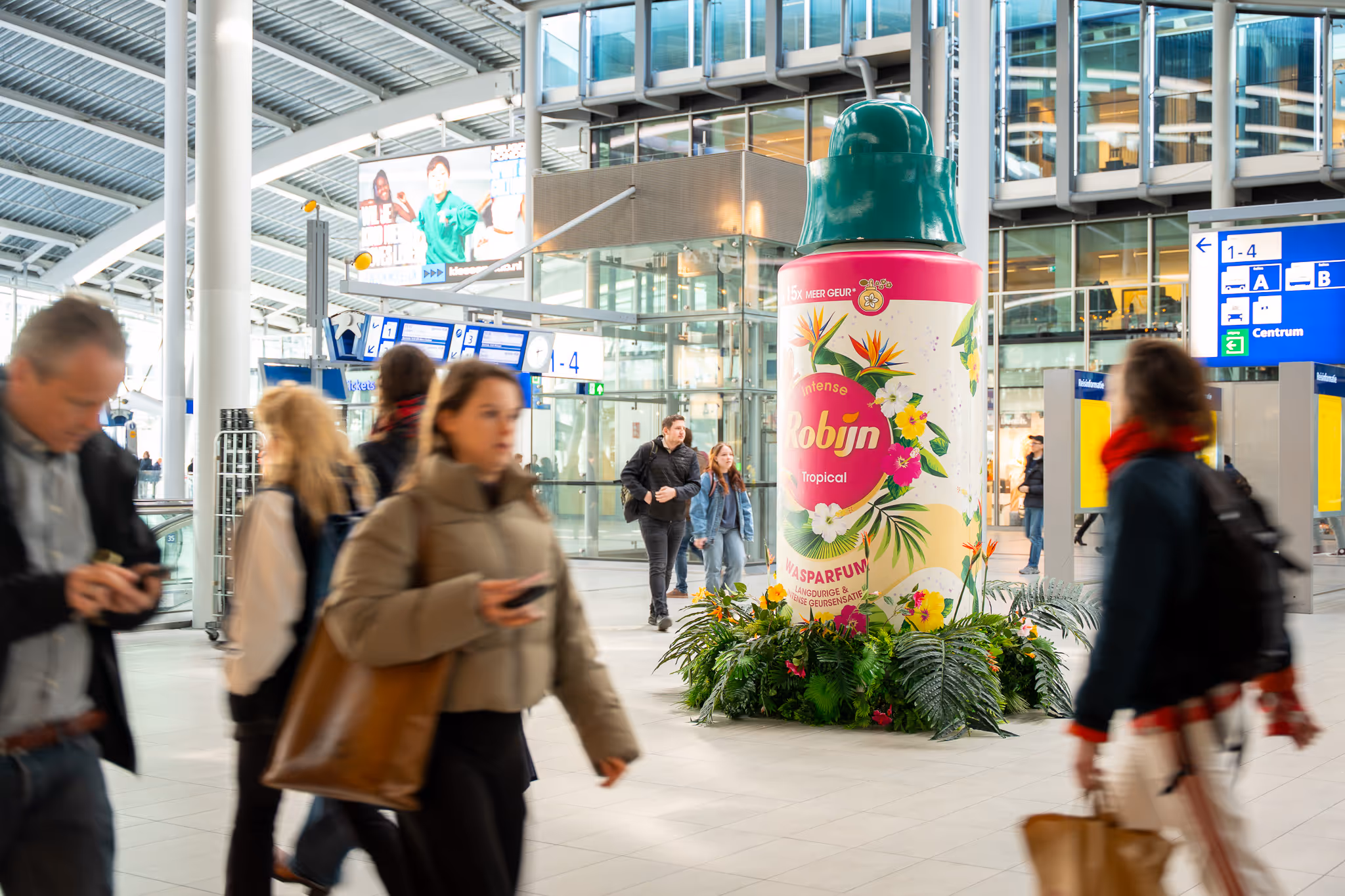 Robijn flacon in groot formaat op treinstation met voorbijgangers