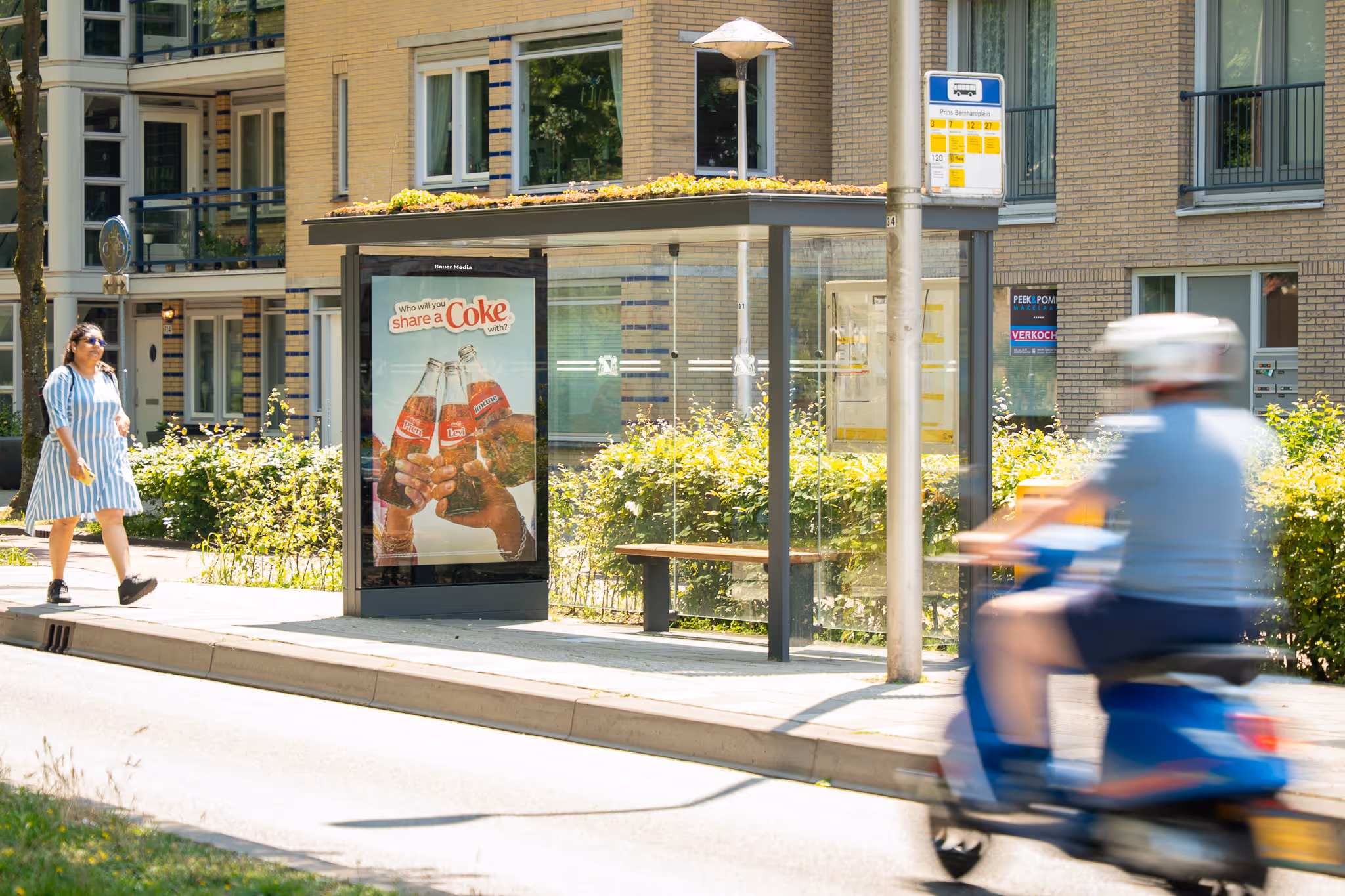 Bushalte met sedum dak en scooter die voorbij rijdt