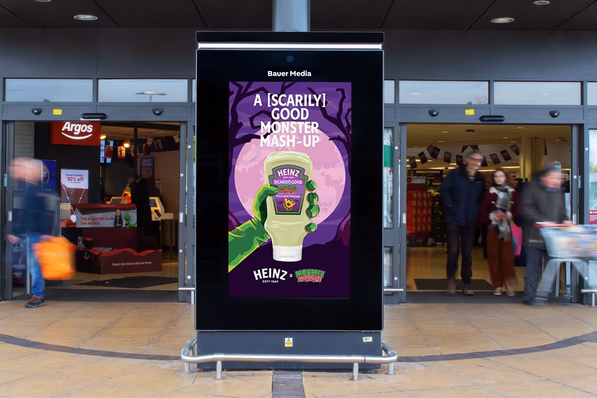 Heinz advert on a digital screen outside a store as shoppers walk in and out