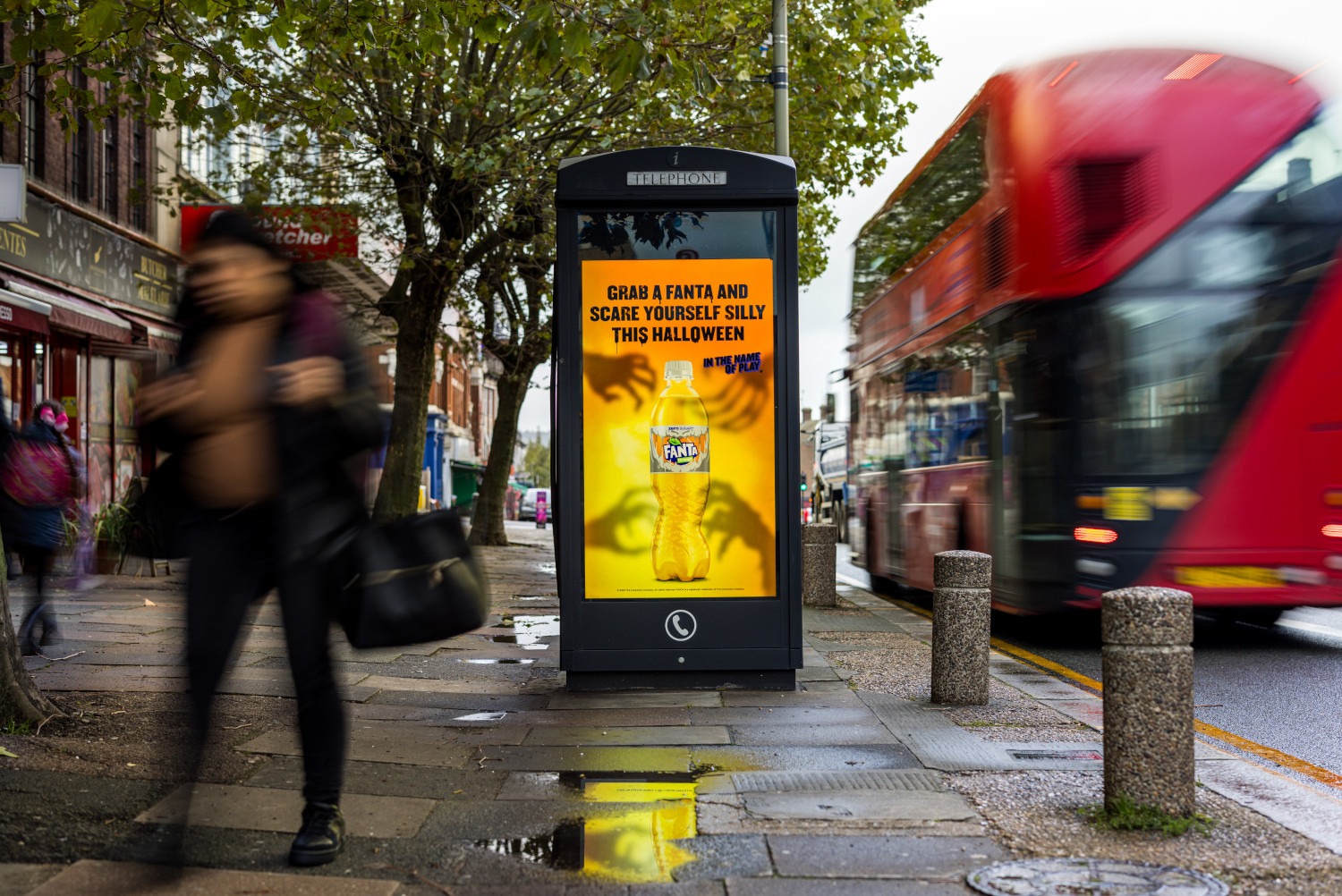 Fanta Halloween advert on a digital screen on a New World Payphone on a busy street as buses and pedestrians pass by during the day