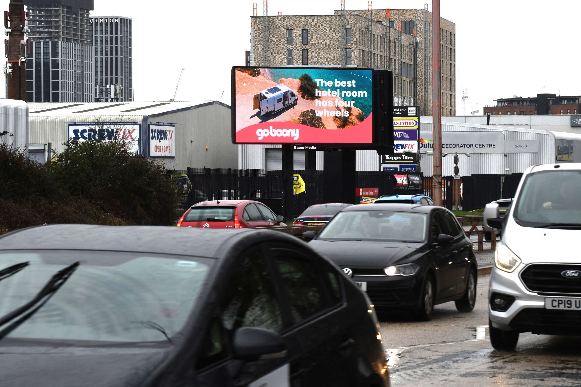 A Billboard Live displaying a hotel brand in front of standing traffic