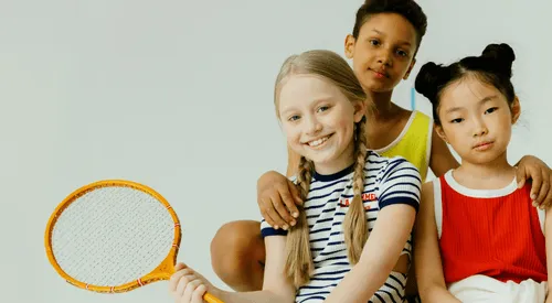 Photo of three happy children from diverse ethnic backgrounds, smiling together.