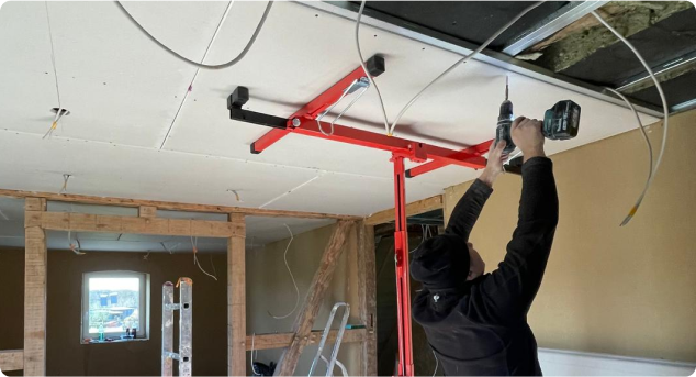 Ein Handwerker in Arbeitskleidung und Schutzhelm führt präzise Trockenbauarbeiten an einer Holzunterkonstruktion aus. Trockenbau ermöglicht eine flexible Raumaufteilung, verbesserten Schallschutz und schnelle Anpassungen an individuelle Wohnbedürfnisse. Ideal für Renovierungen, Umbauten und Neubauprojekte im Innenbereich. Effizient, sauber und vielseitig einsetzbar.
