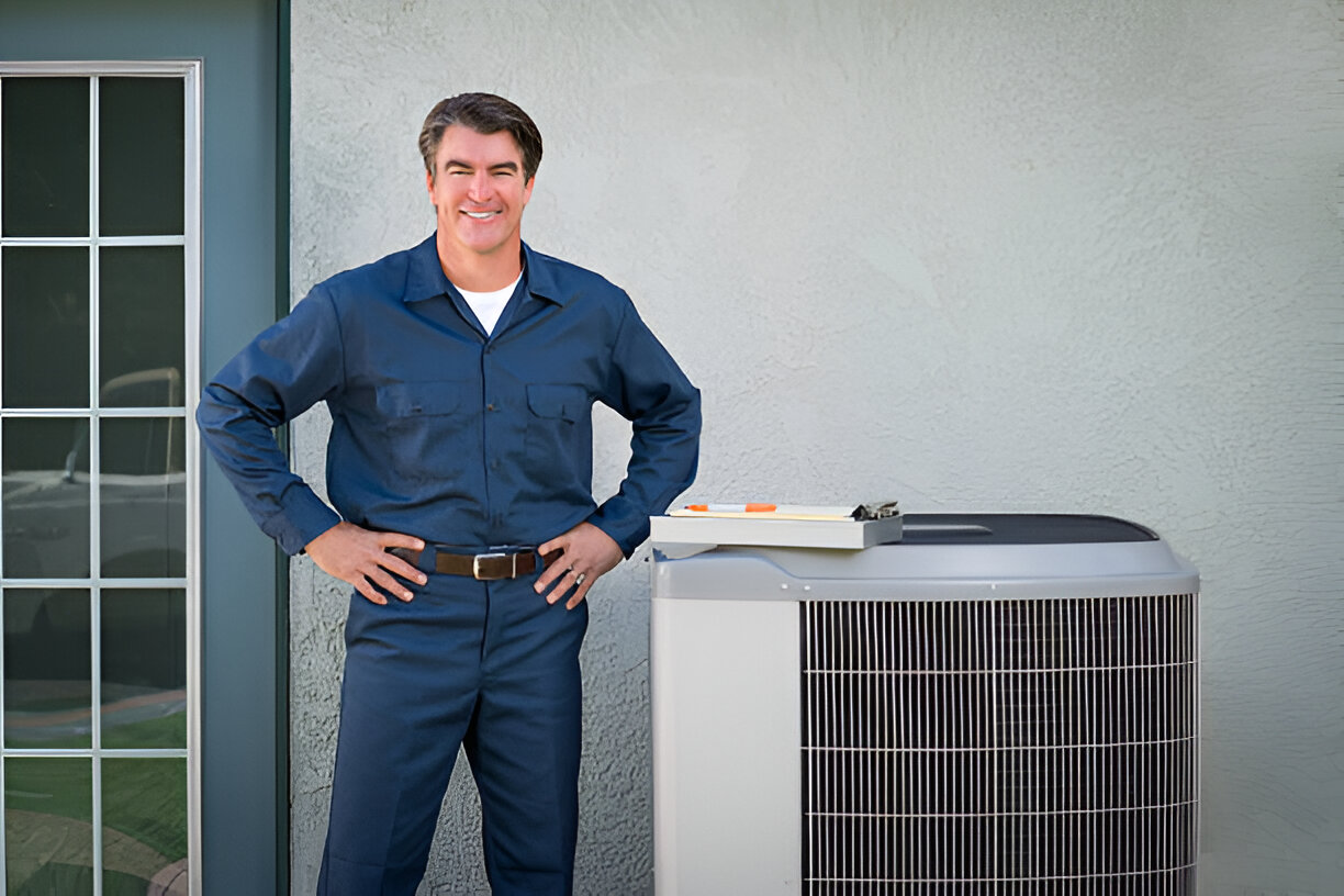 HVAC technician smiling next to air conditioning unit outside building