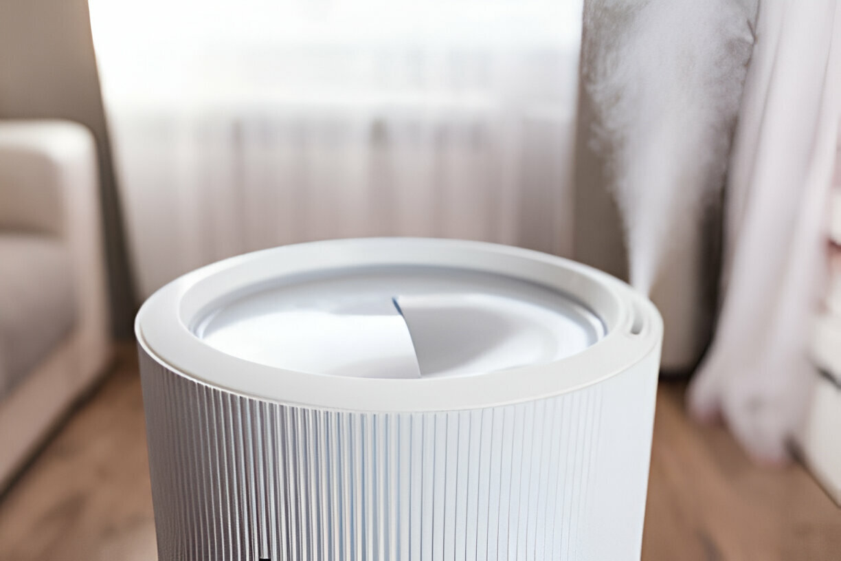 White cylindrical air purifier with ribbed design on wooden floor