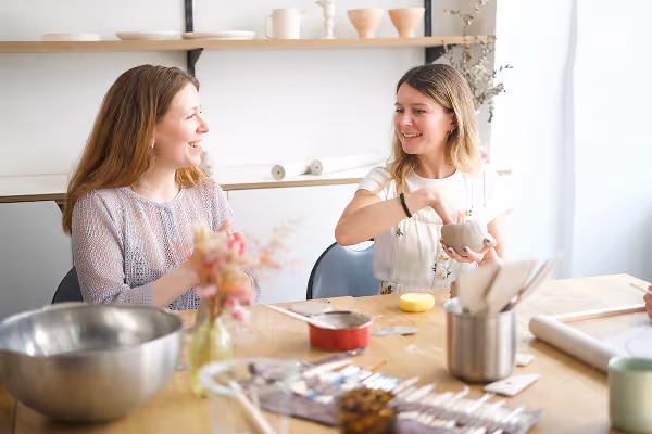 Deux femmes souriantes participent à un atelier créatif de céramique.