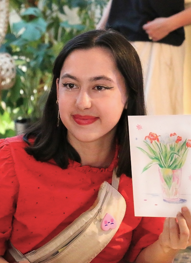 Main dessinant au crayon sur un carnet de croquis avec plusieurs crayons flous en arrière-plan.