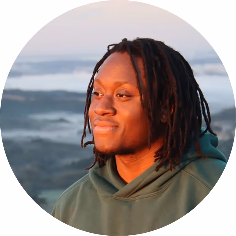 Smiling young man with dreadlocks and misty mountain backdrop, round portrait.