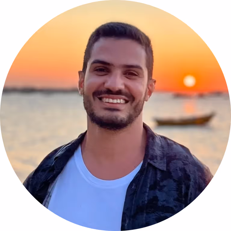 Smiling young man with short beard at beach sunset, round portrait.