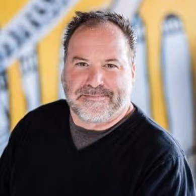 Professional headshot of a bearded man in a black shirt.
