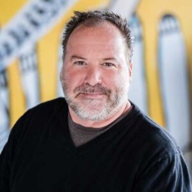 Professional headshot of a bearded man in a black shirt.