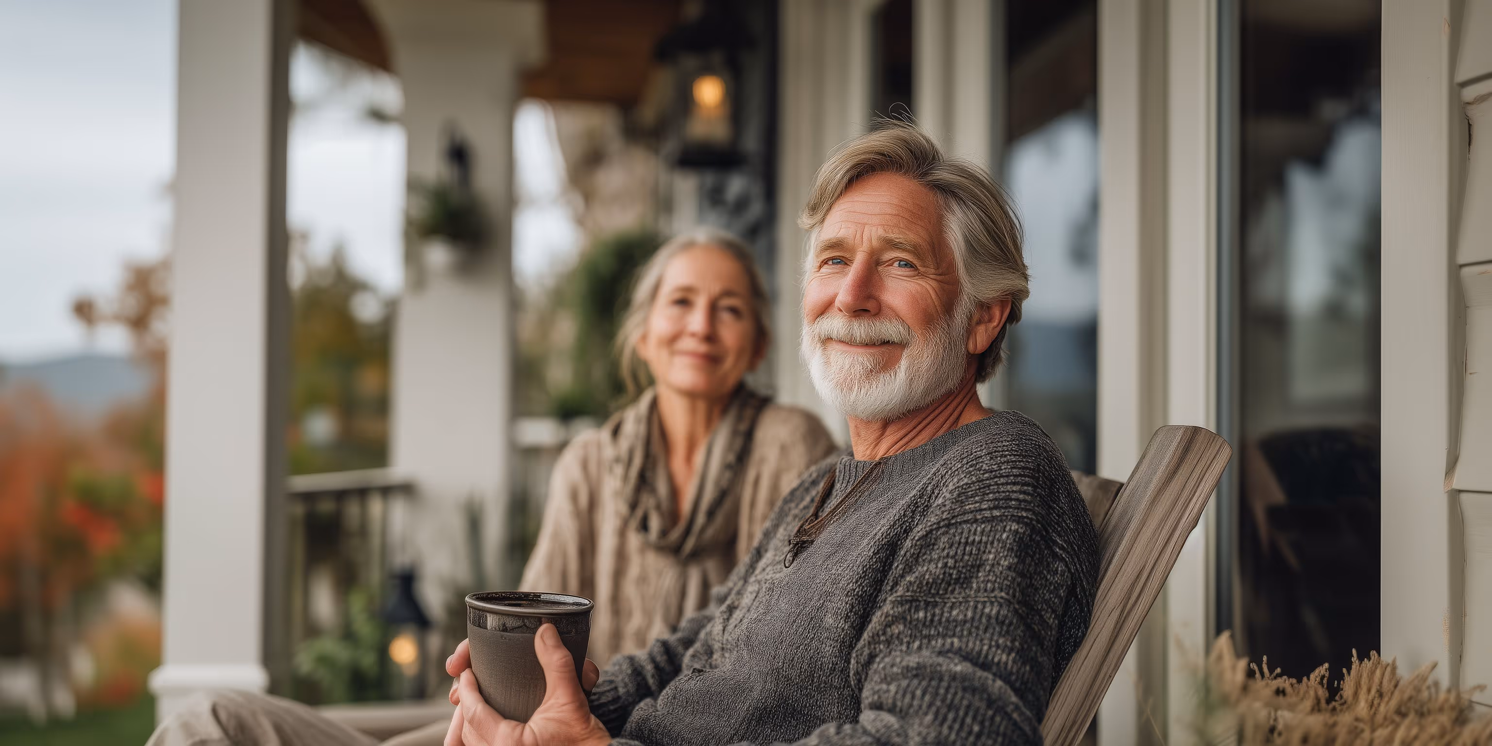 Photo of a happy, retired couple relaxing and drinking coffee on their front porch, symbolizing a secure, stress-free aging in place lifestyle achieved through home equity access.