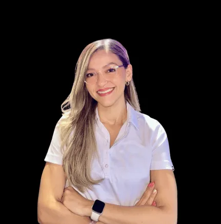 Smiling woman with long blonde hair, wearing glasses and a white shirt, arms crossed.