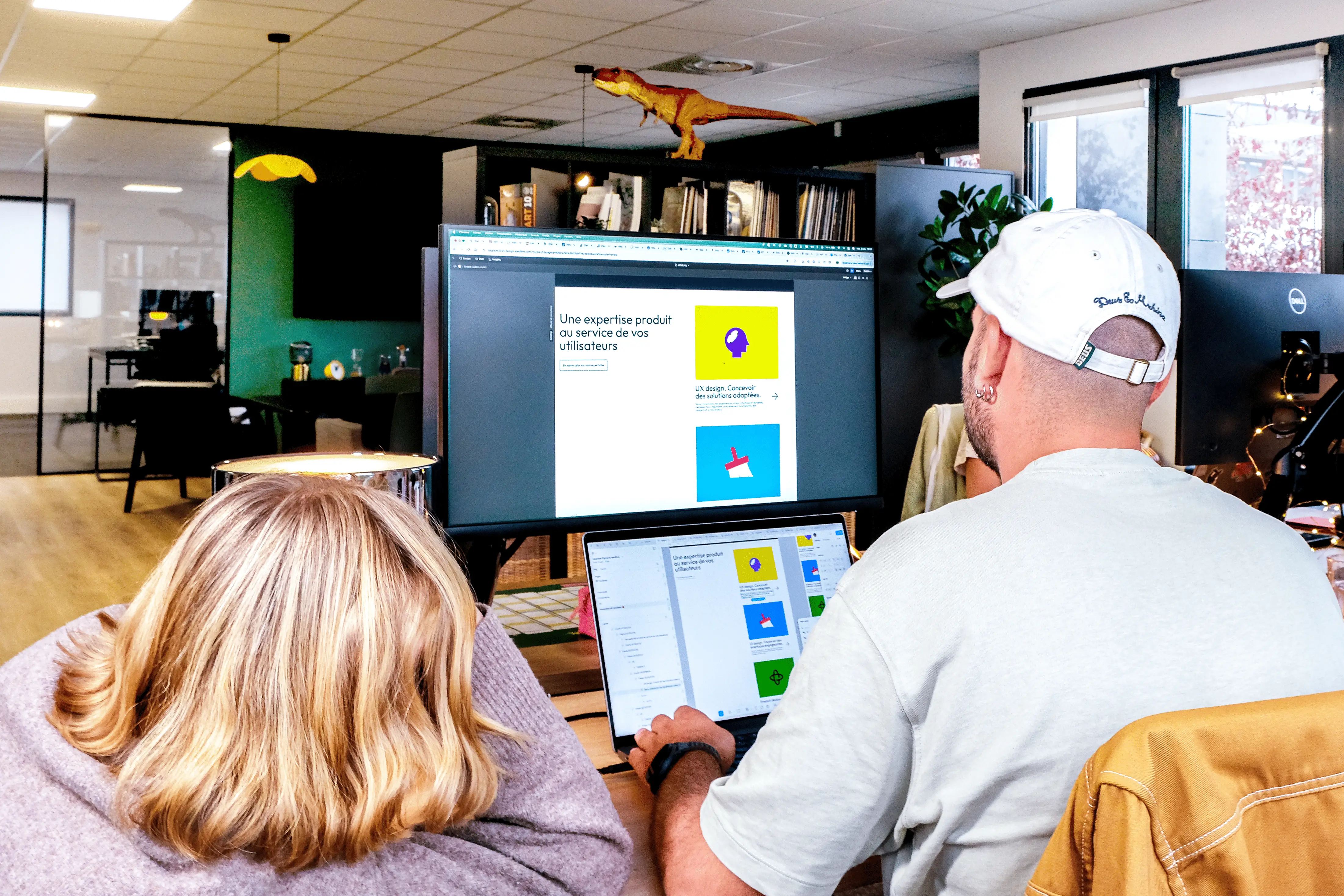 Deux designers de l'agence design UX UI Upgrade à Nantes examinant un écran affichant des maquettes et des interfaces utilisateur UI en cours de conception.